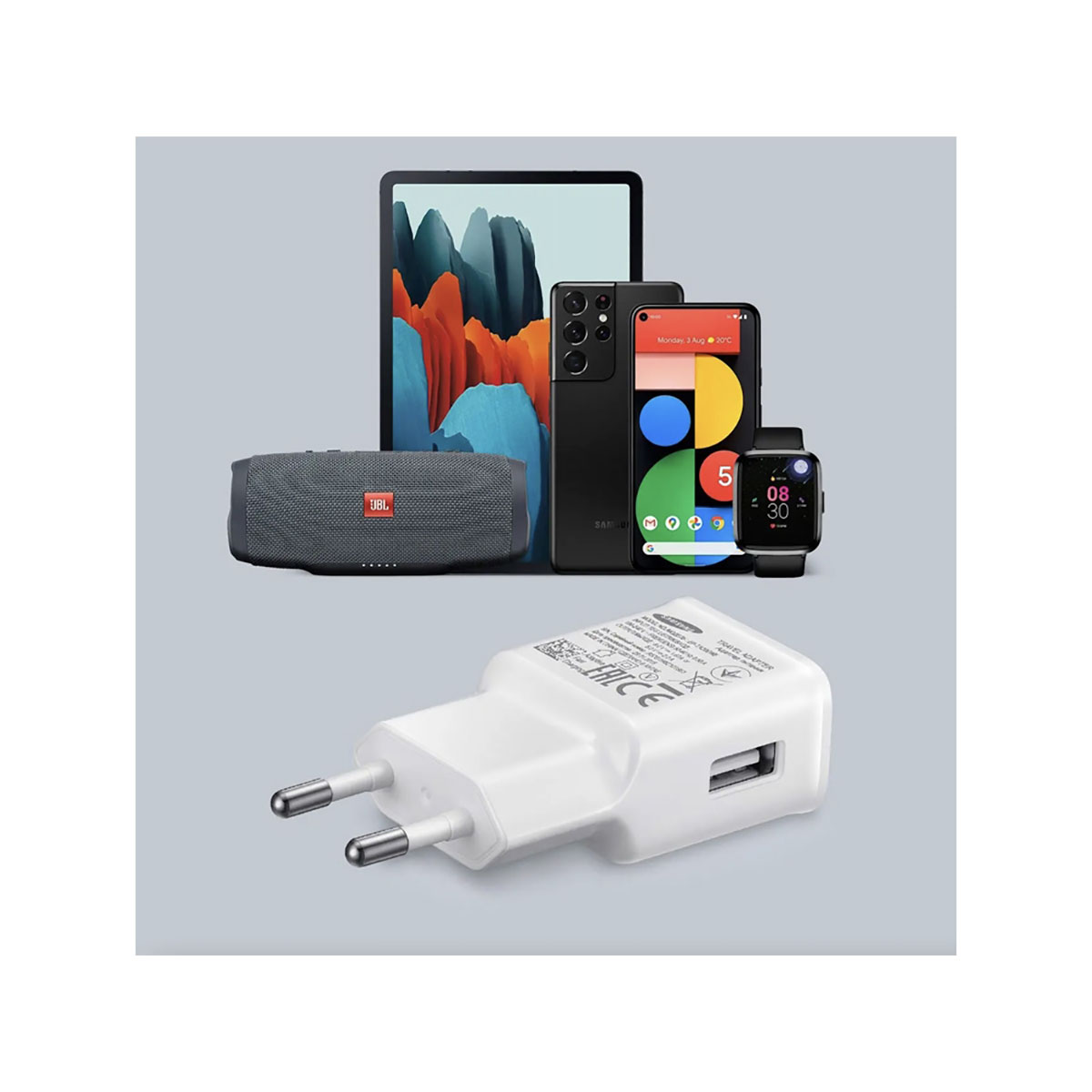 Un chargeur blanc avec deux broches et un port USB est au premier plan. Derrière, il y a une tablette, un téléphone, une montre et un haut-parleur JBL.