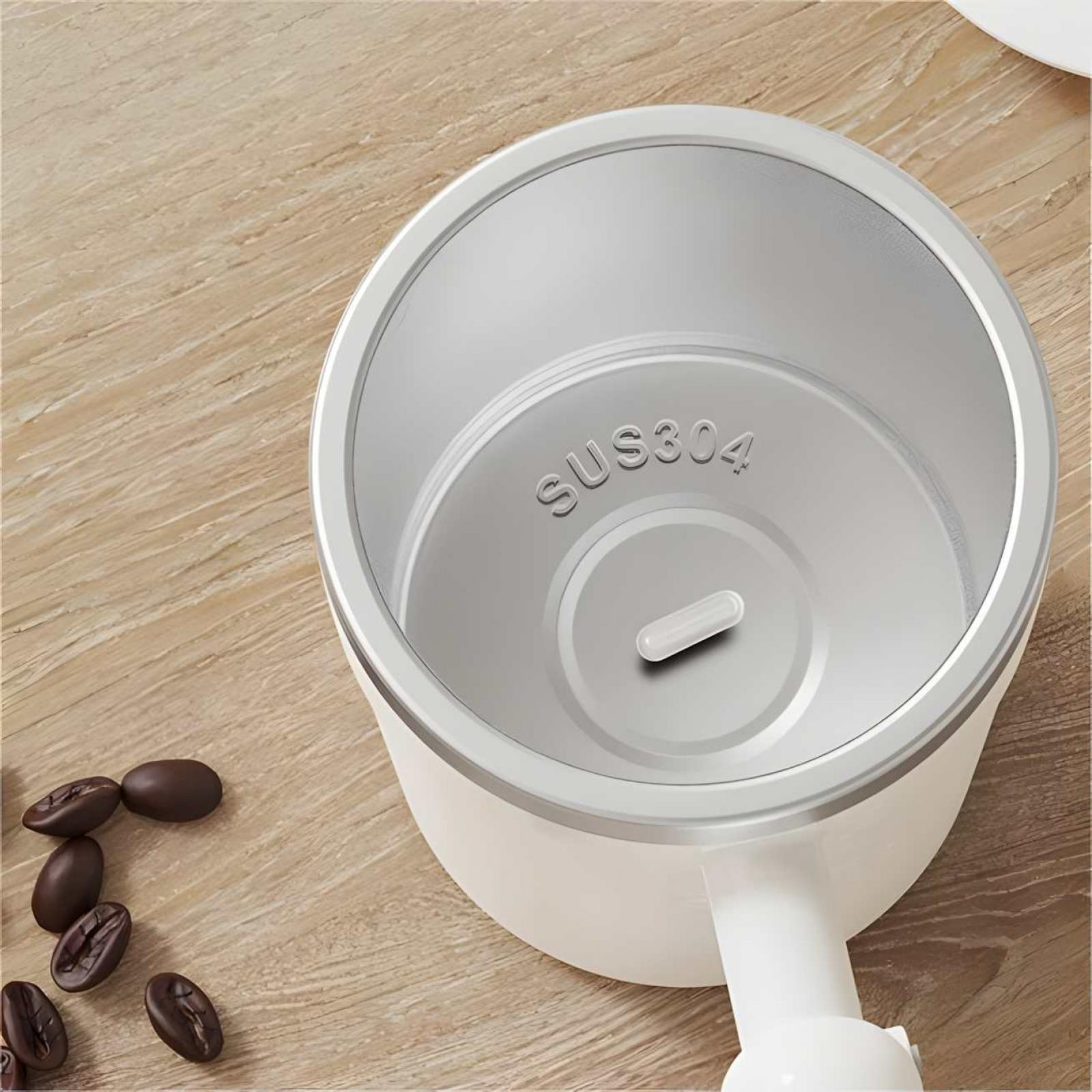 Ein weißer und silberner Kaffeezubereiter, mehrere Kaffeebohnen auf einer Holzoberfläche. Das Innere des Kaffeezubereiters ist sichtbar.