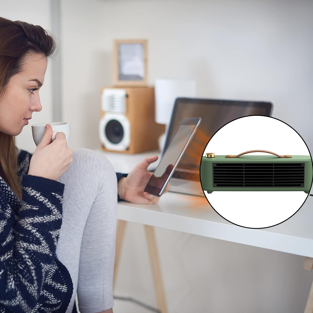 Frau trinkt aus einer Tasse, benutzt ein Tablet, mit einem grünen Heizgerät auf einem Schreibtisch. Laptop und Lautsprecher sind ebenfalls vorhanden.