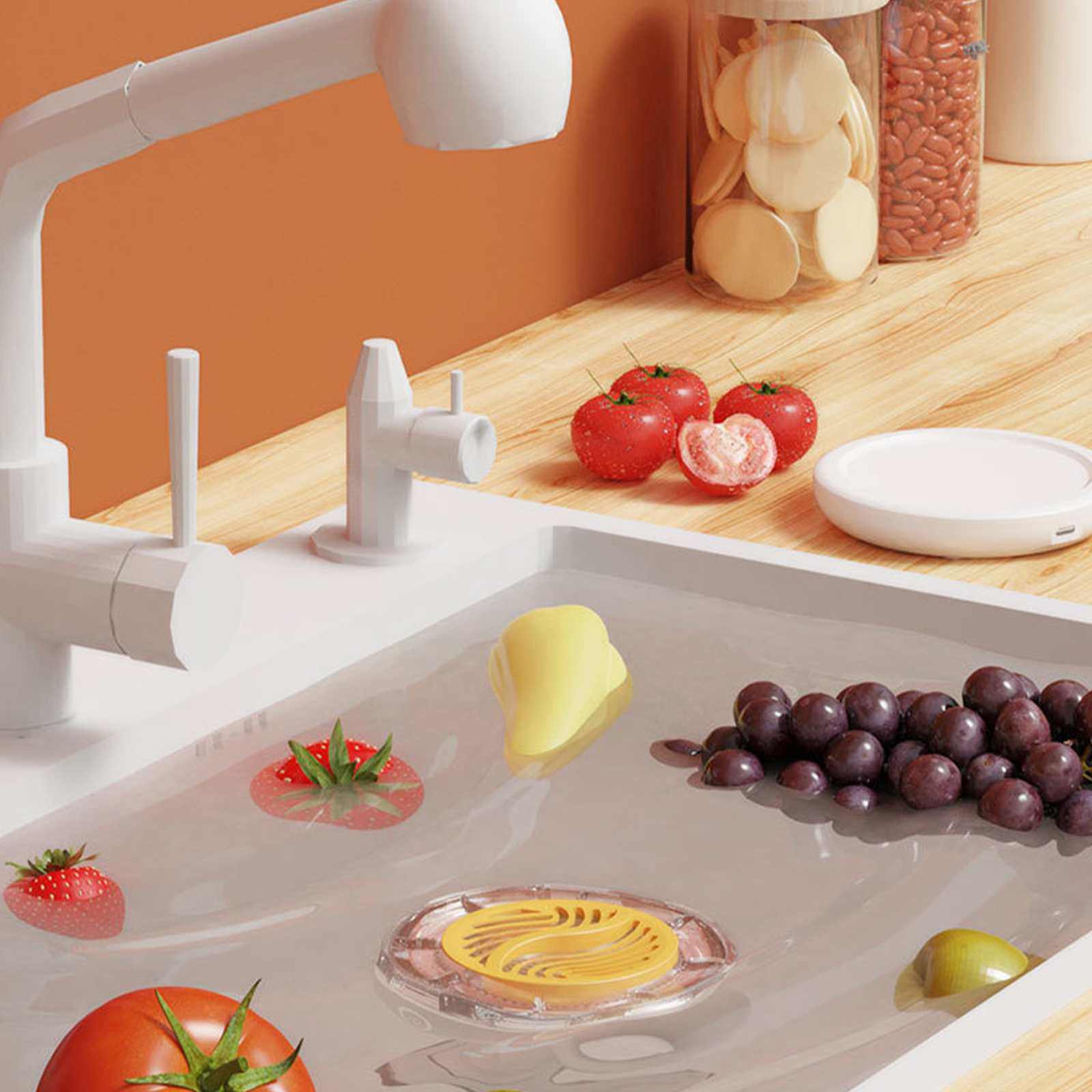 Ein weißes Waschbecken mit Früchten im Wasser: Tomaten, Trauben, Erdbeere und eine mangoartige Frucht. Darüber ein weißer Wasserhahn.
