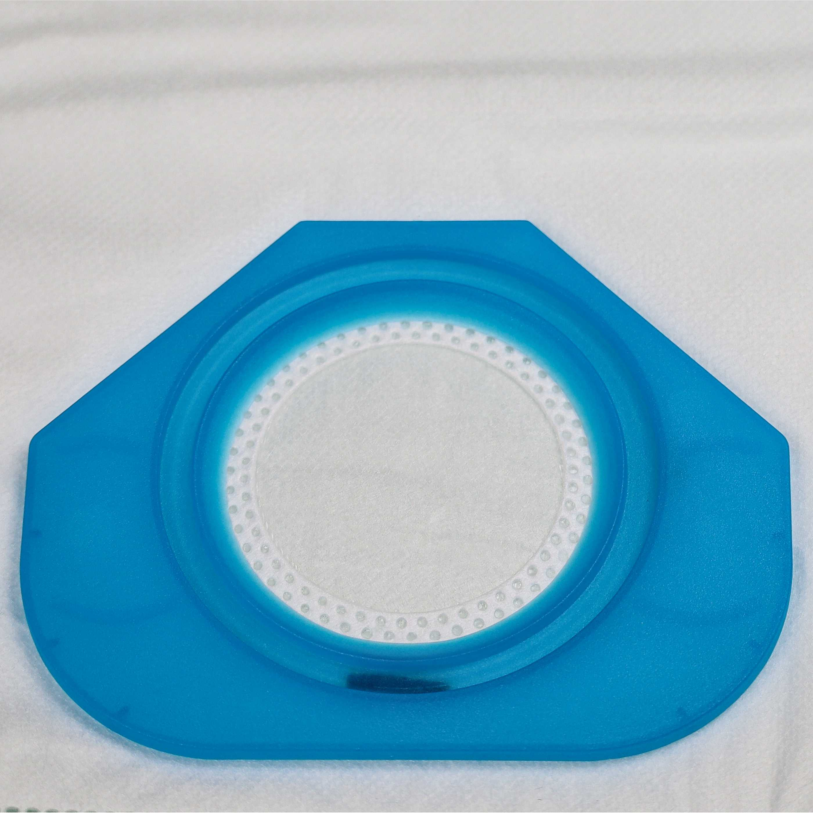Ein blauer Kunststofffilter mit weißer Mitte und hellem Hintergrund. Der Filter hat eine sechseckige Form.