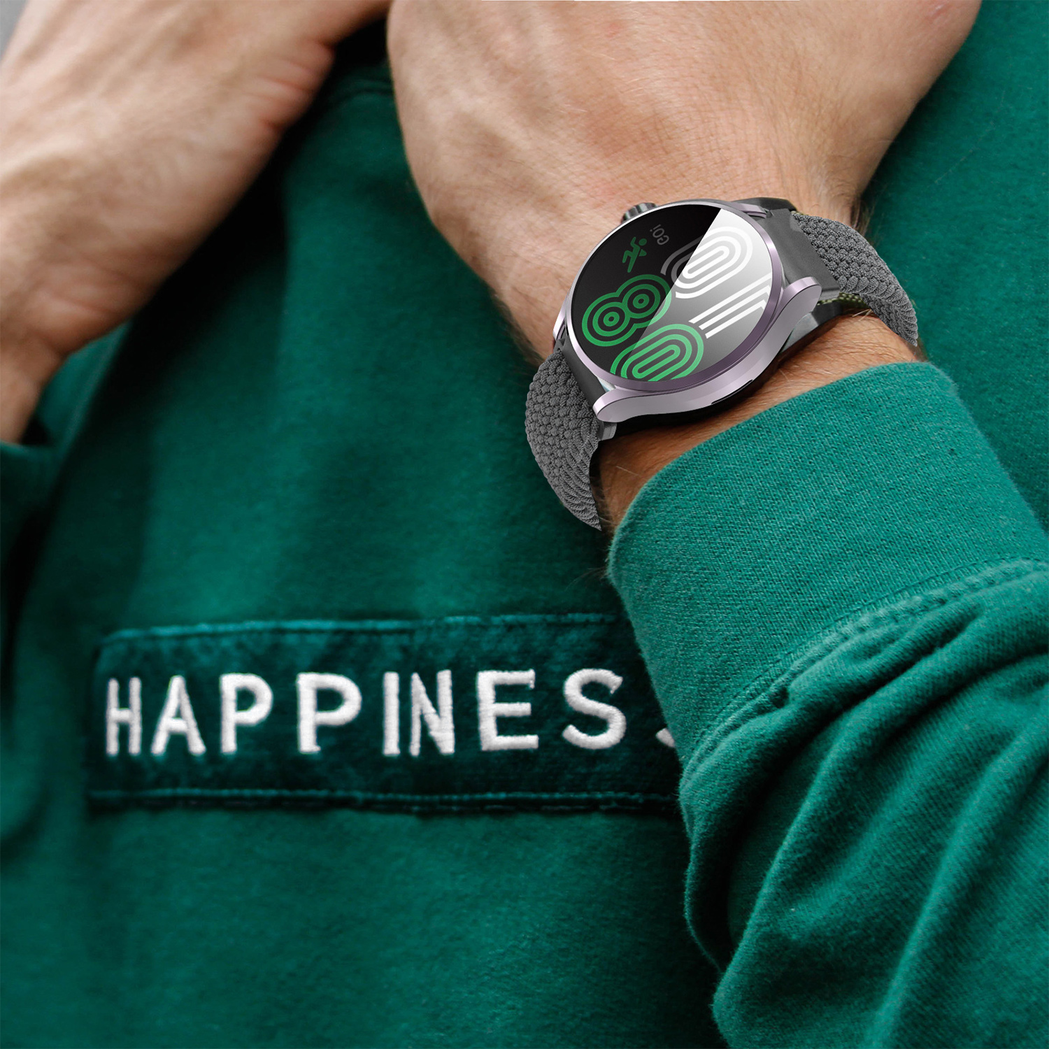 Osoba nosząca smartwatch na nadgarstku, zielony sweter z napisem HAPPINESS.