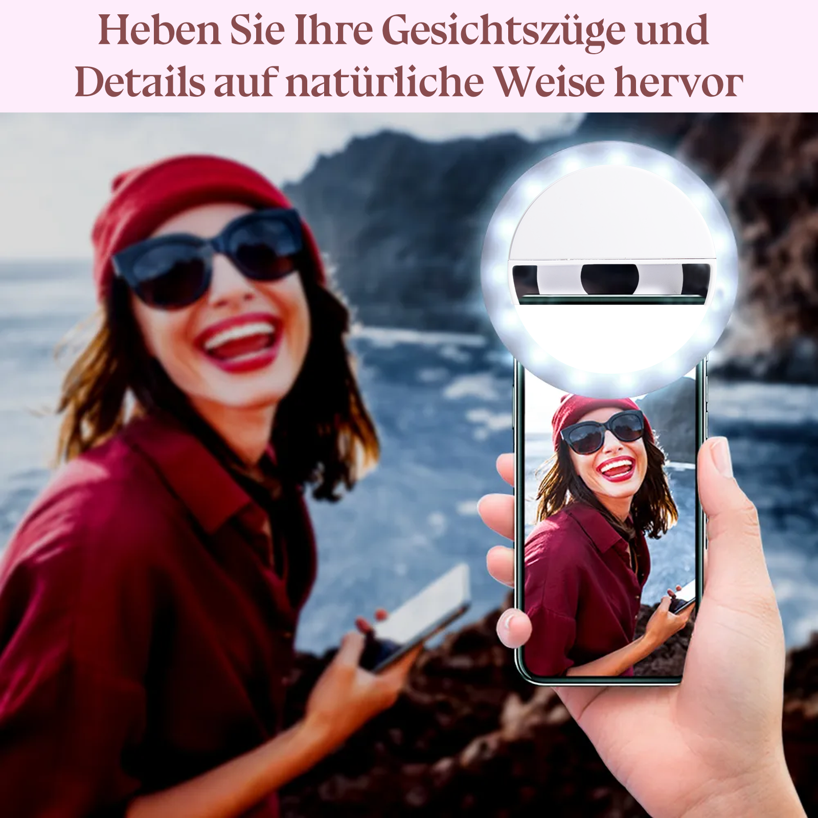 Frau mit Sonnenbrille und roter Mütze lacht, hält Telefon mit Ringlicht. Hintergrund ist verschwommenes Meer und Klippen.
