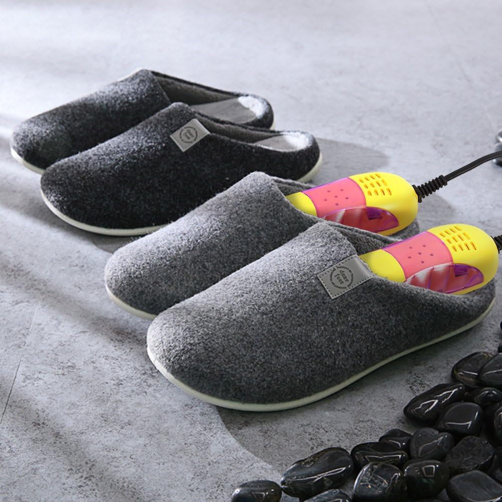 Drei Paar graue Hausschuhe, einer mit einem Schuhtrockner. Schwarze Kieselsteine befinden sich unten rechts. Die Hausschuhe liegen auf einer grauen Oberfläche.