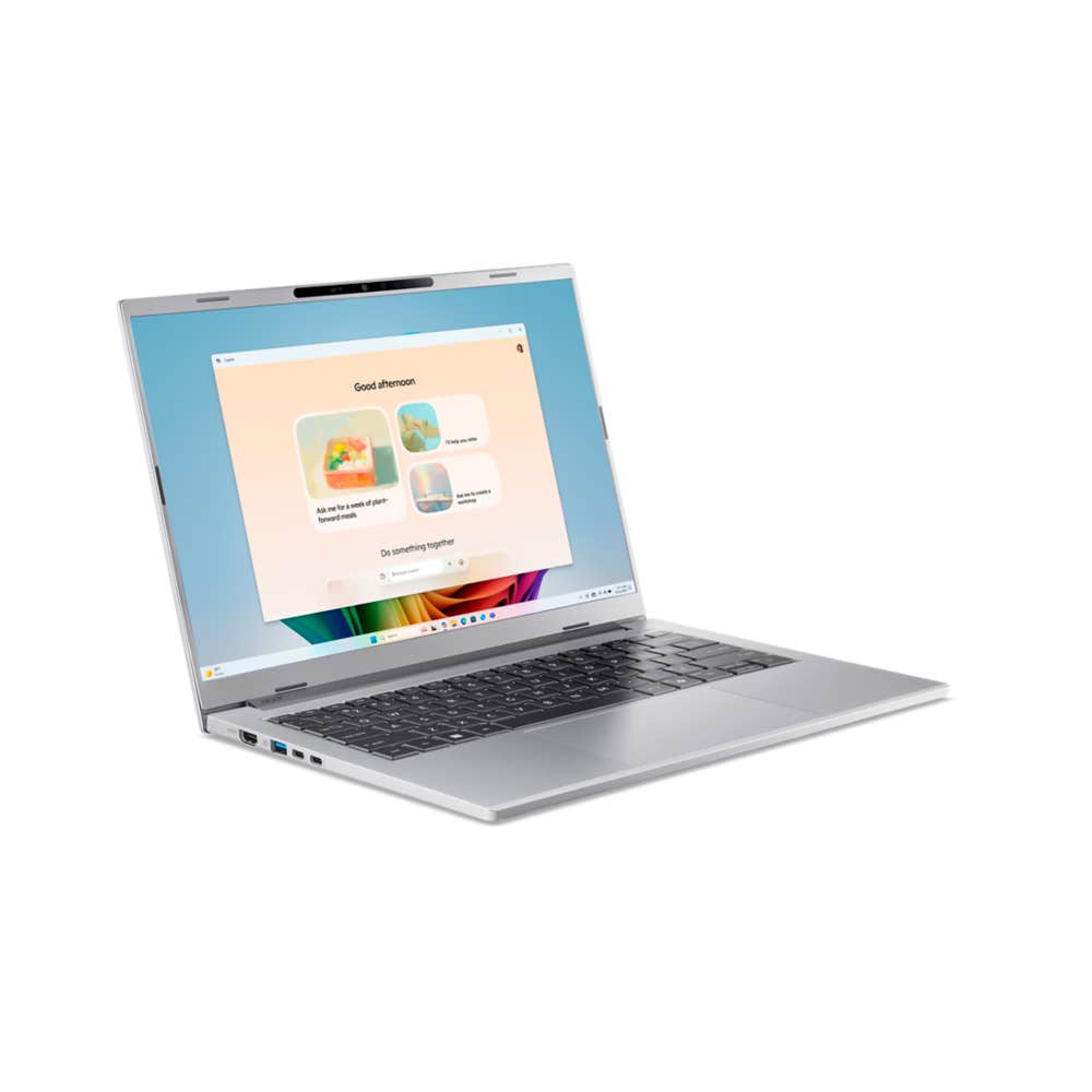 Otwarty srebrny laptop, wyświetlający ekran powitalny Windows. Klawiatura czarna, ekran pokazuje kolorową grafikę na niebieskim tle.