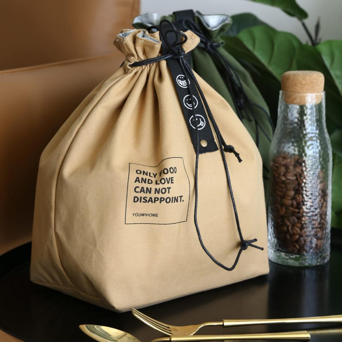 Beige Kordelzugtasche mit Text. Kaffeebohnen in einem Glas. Goldenes Besteck auf schwarzer Oberfläche.