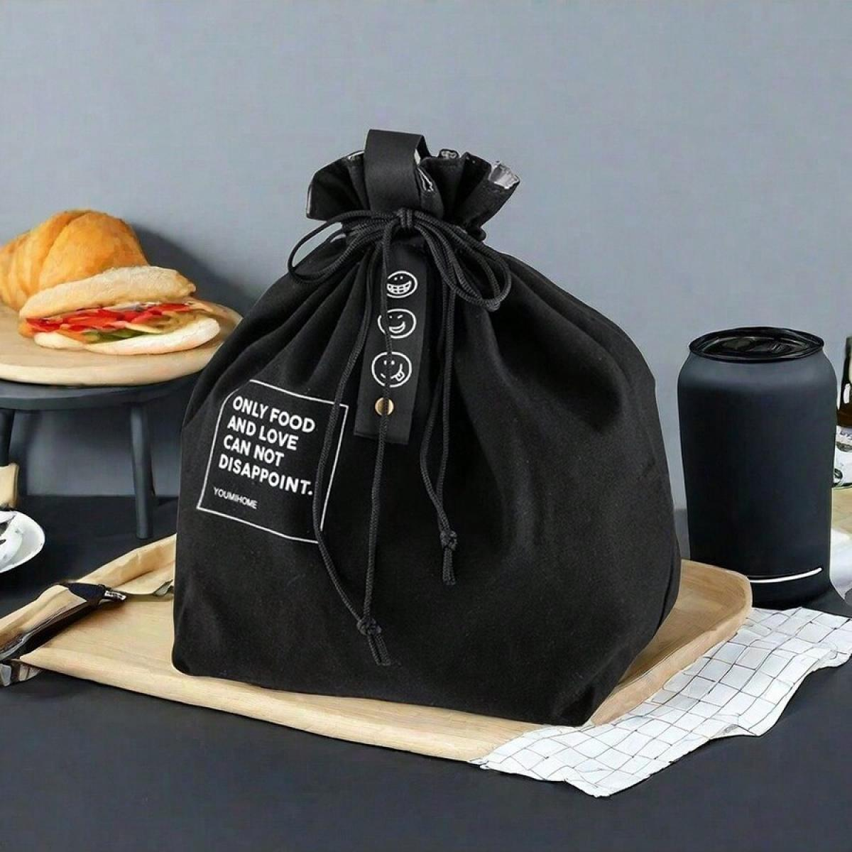 Eine schwarze Lunchtasche mit Kordelzug, ein Sandwich und eine schwarze Thermoskanne auf einem Holztablett. Die Tasche hat ein Etikett mit 'Only Food and Love'.