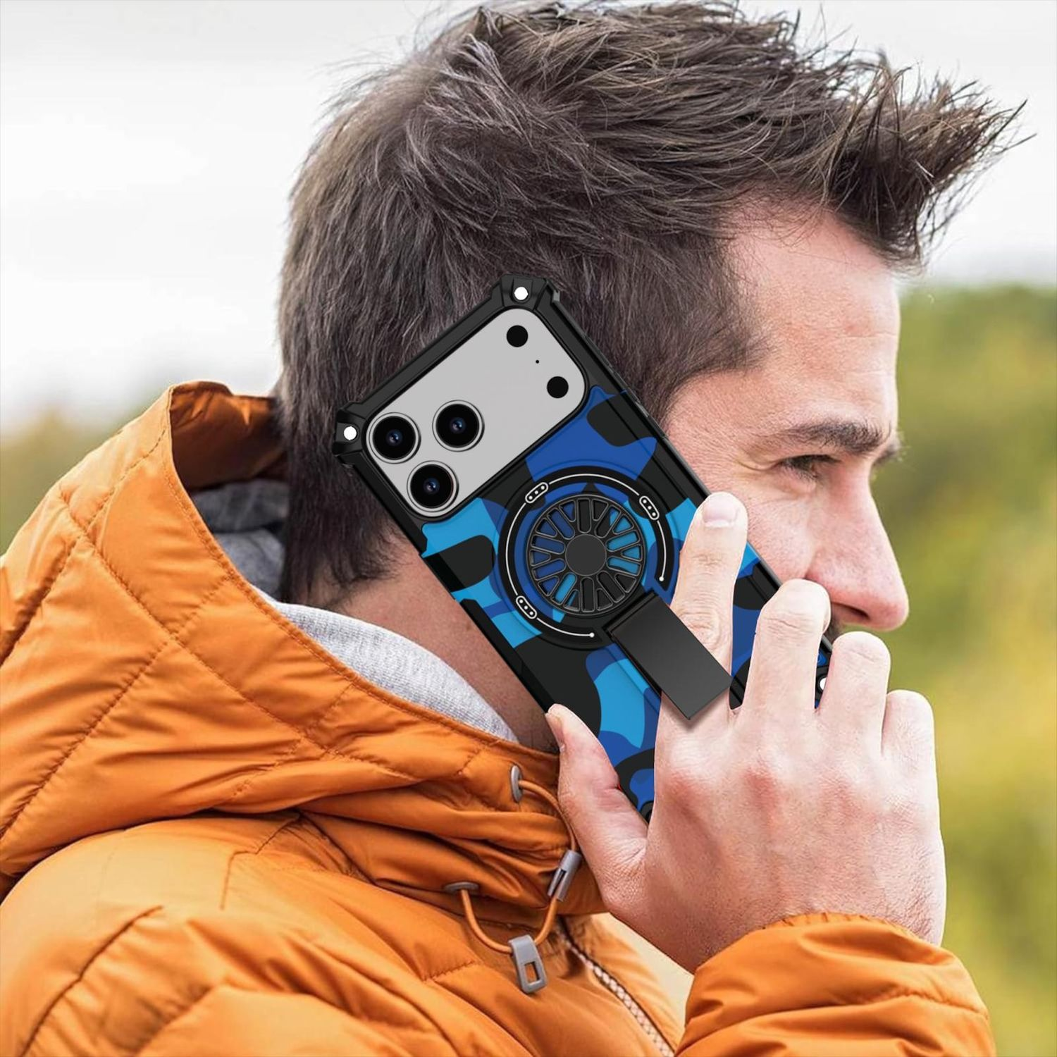 Mann telefoniert mit blauem Tarnmuster-Handy. Er trägt eine orangefarbene Jacke. Das Telefon hat einen Lüfter auf der Rückseite. Grüner Hintergrund.