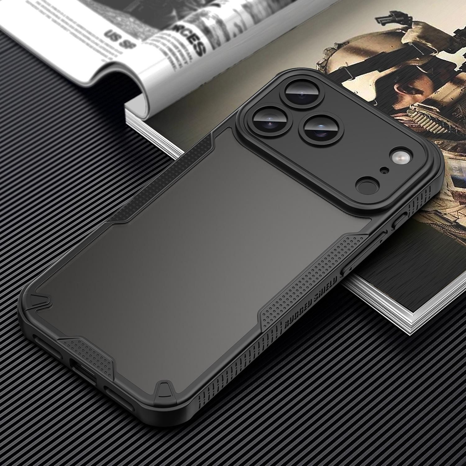 Funda negra para teléfono con lentes de triple cámara, sobre una revista. El fondo presenta una superficie oscura y estampada.