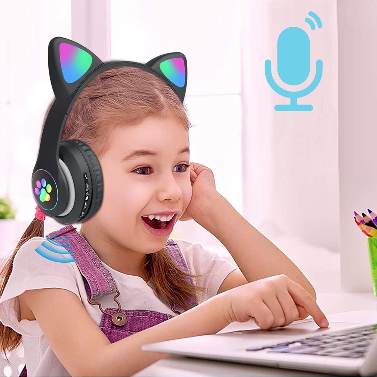 Ein Mädchen mit Katzenohrhörern, lächelt auf einen Laptop. Ein Mikrofonsymbol und Buntstifte sind im Hintergrund zu sehen.