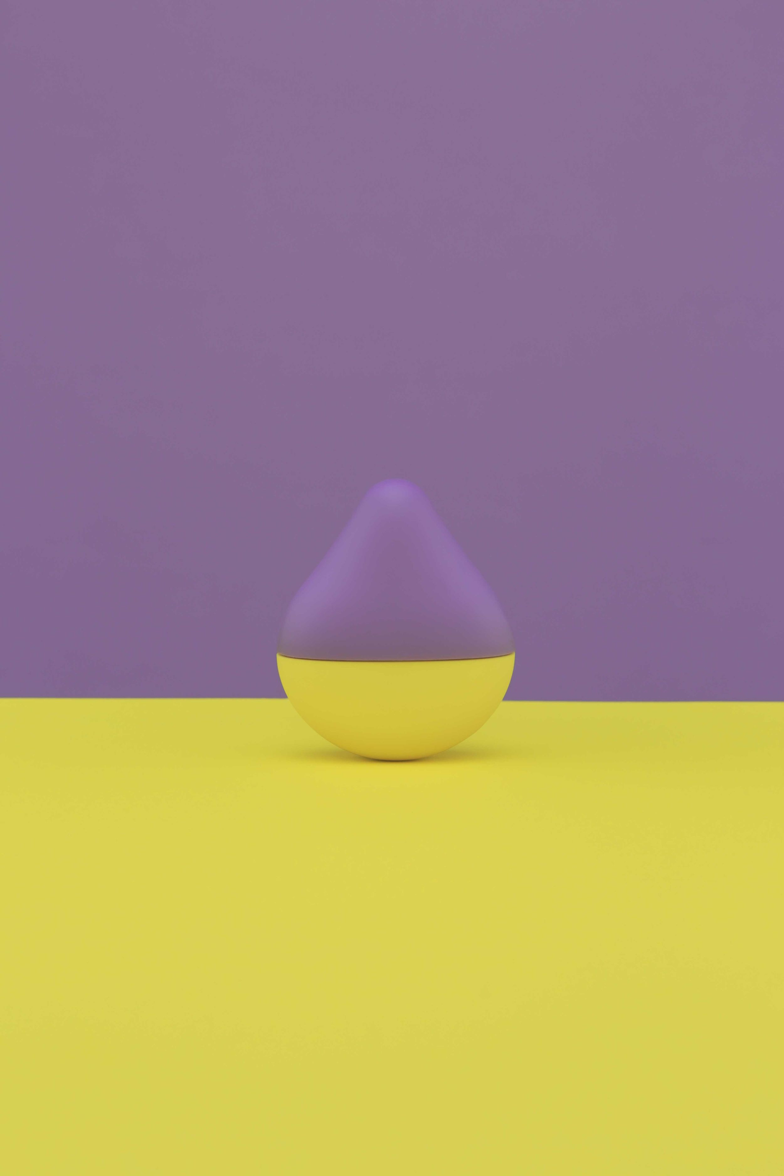 Żółty i fioletowy obiekt w kształcie łzy na żółtym i fioletowym tle.