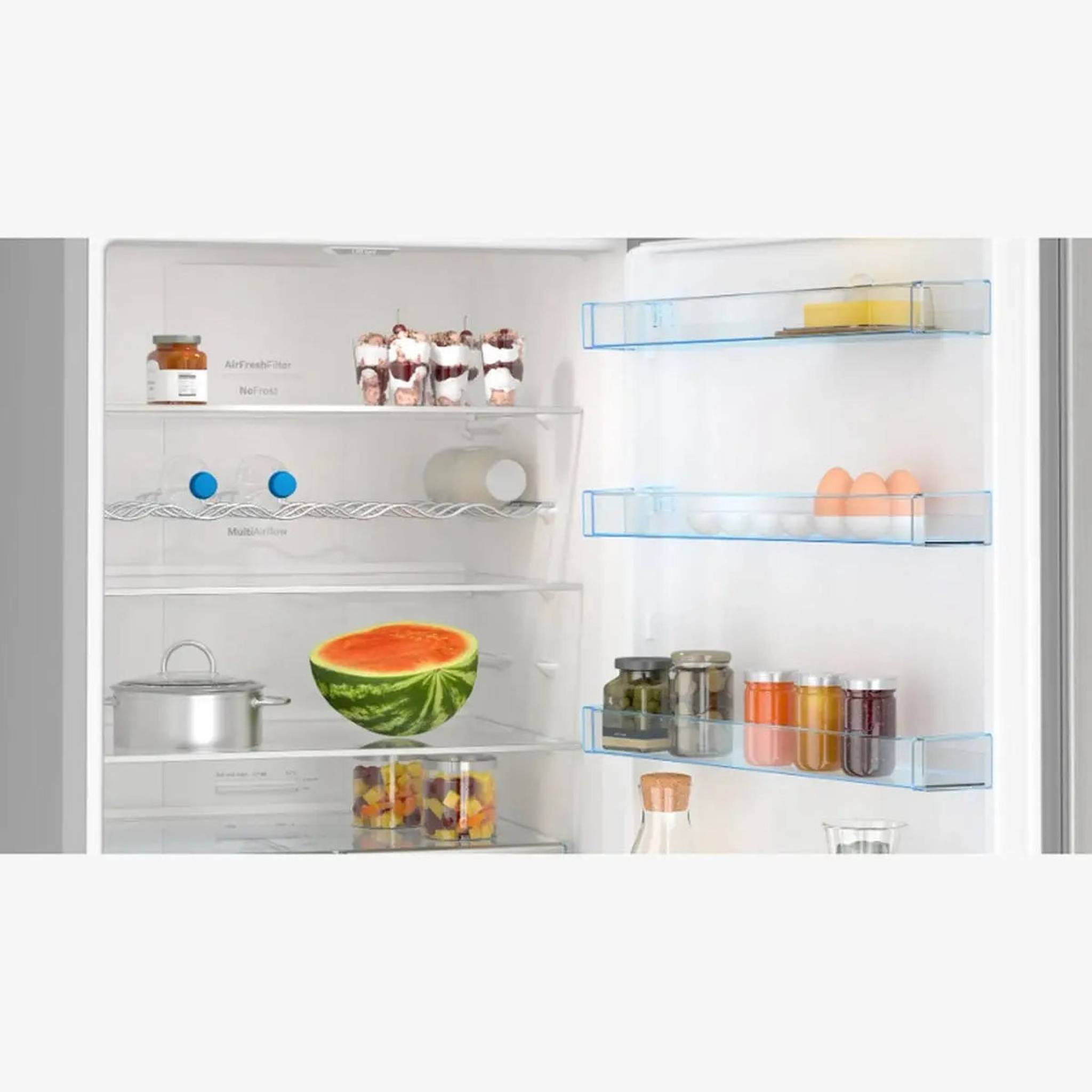 W lodówce: arbuz, słoiki z jedzeniem, jajka, desery i garnek. Półki zawierają różne przedmioty.