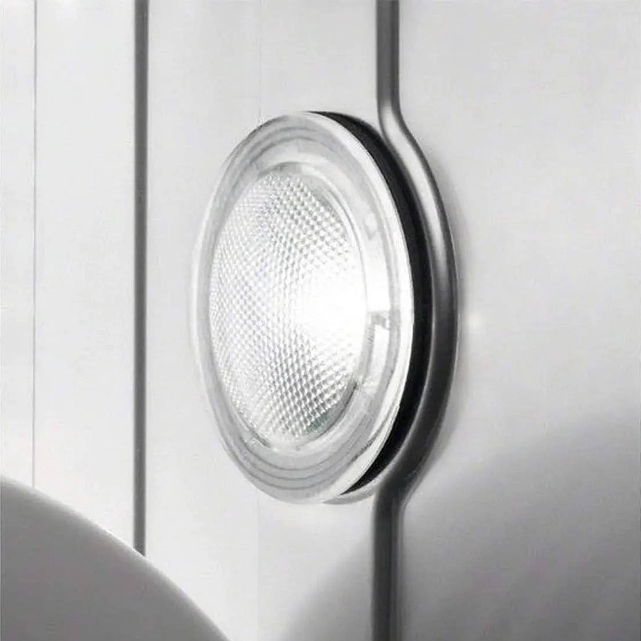 Gros plan d'un luminaire LED rond et transparent sur une surface blanche, avec un accent métallique.