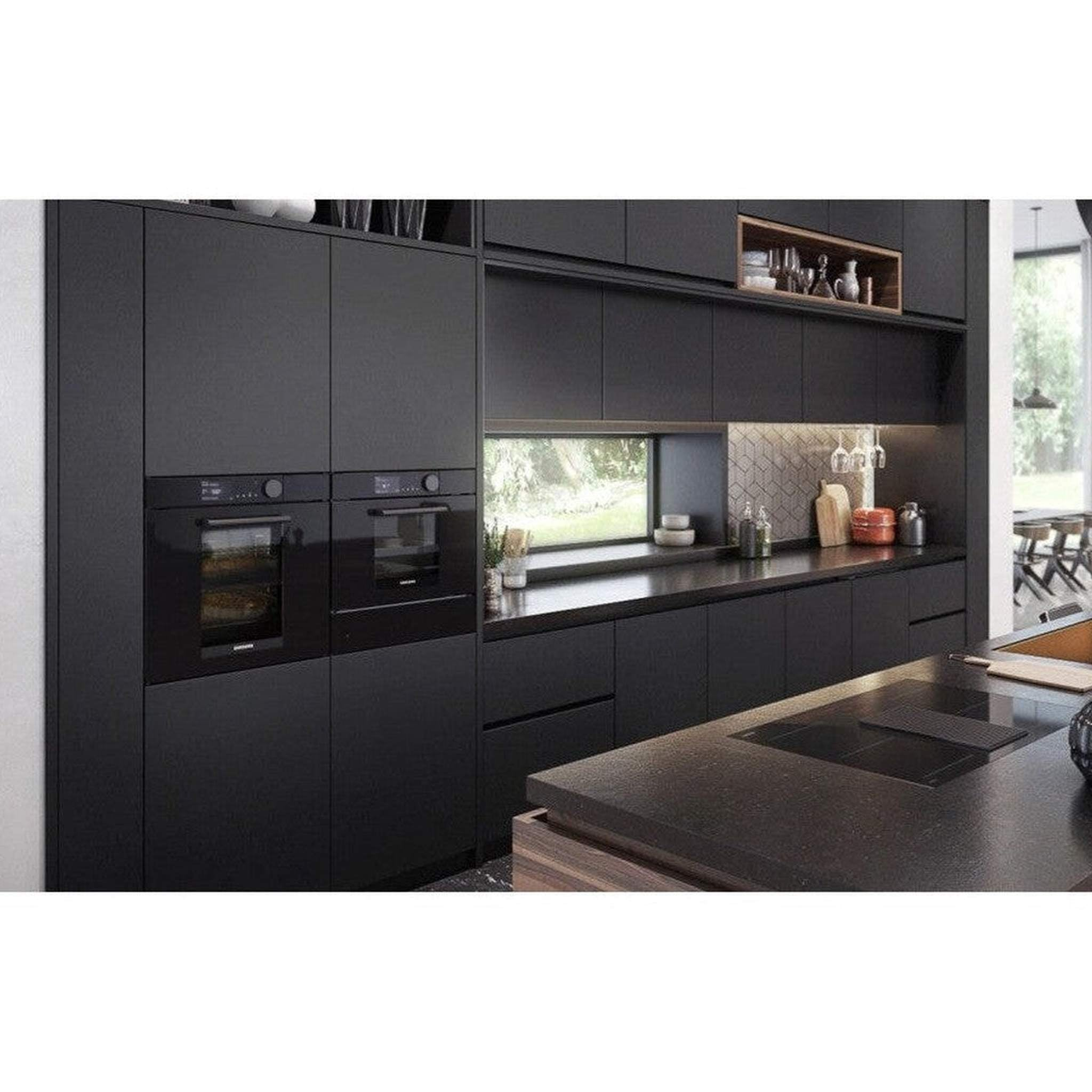 Cuisine noire moderne avec fours, placards et îlot. Une fenêtre montre la vue extérieure. Verrerie et décor sont visibles.