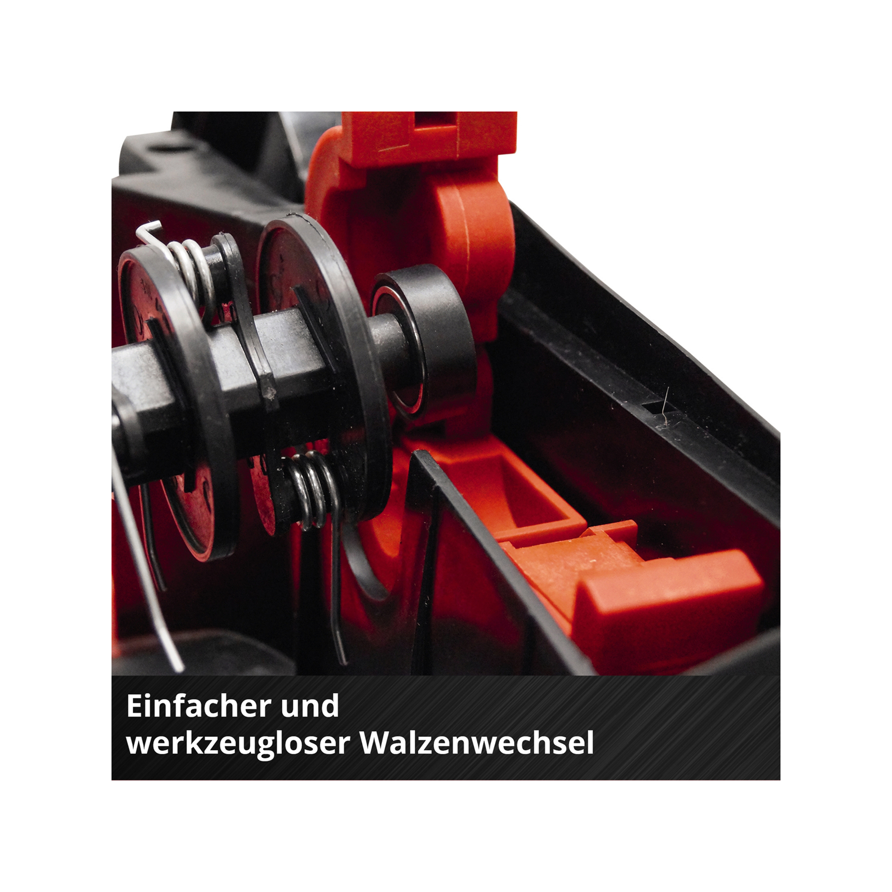 Nahaufnahme von Innenteilen einer Maschine. Schwarze und rote Komponenten, Walze, Federn und Gehäuse. Text unten.