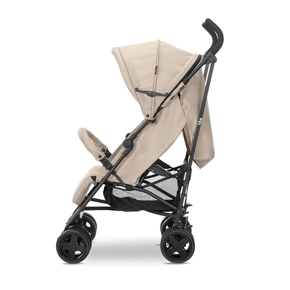 Ein beiger Kinderwagen ist von der Seite zu sehen. Er hat ein Verdeck, einen Sitz und einen Aufbewahrungskorb. Das Gestell ist schwarz. Vier schwarze Räder.