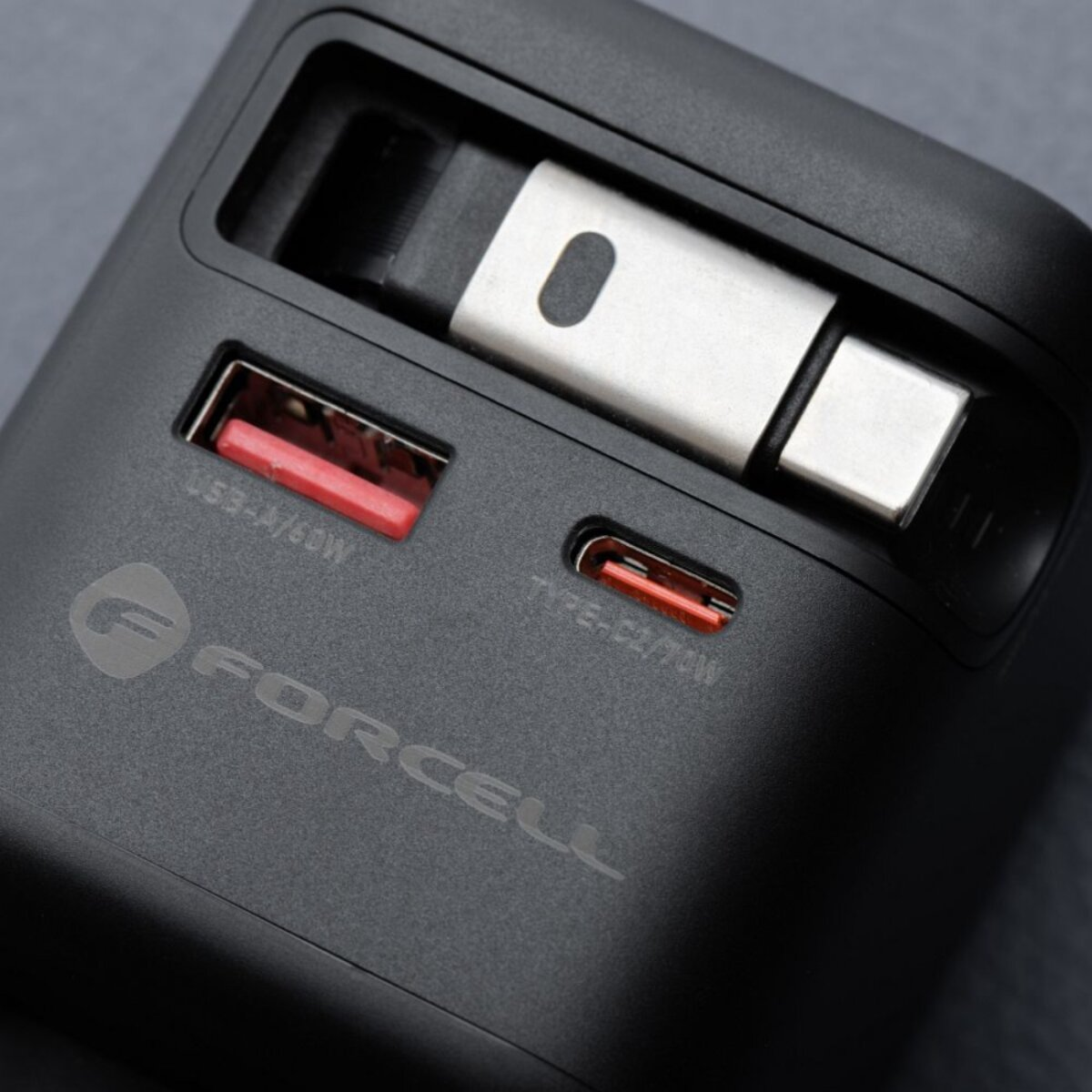 Caricabatterie Forcell nero con porte USB e USB-C. Le porte hanno inserti rossi. Pezzo di metallo argentato in alto.