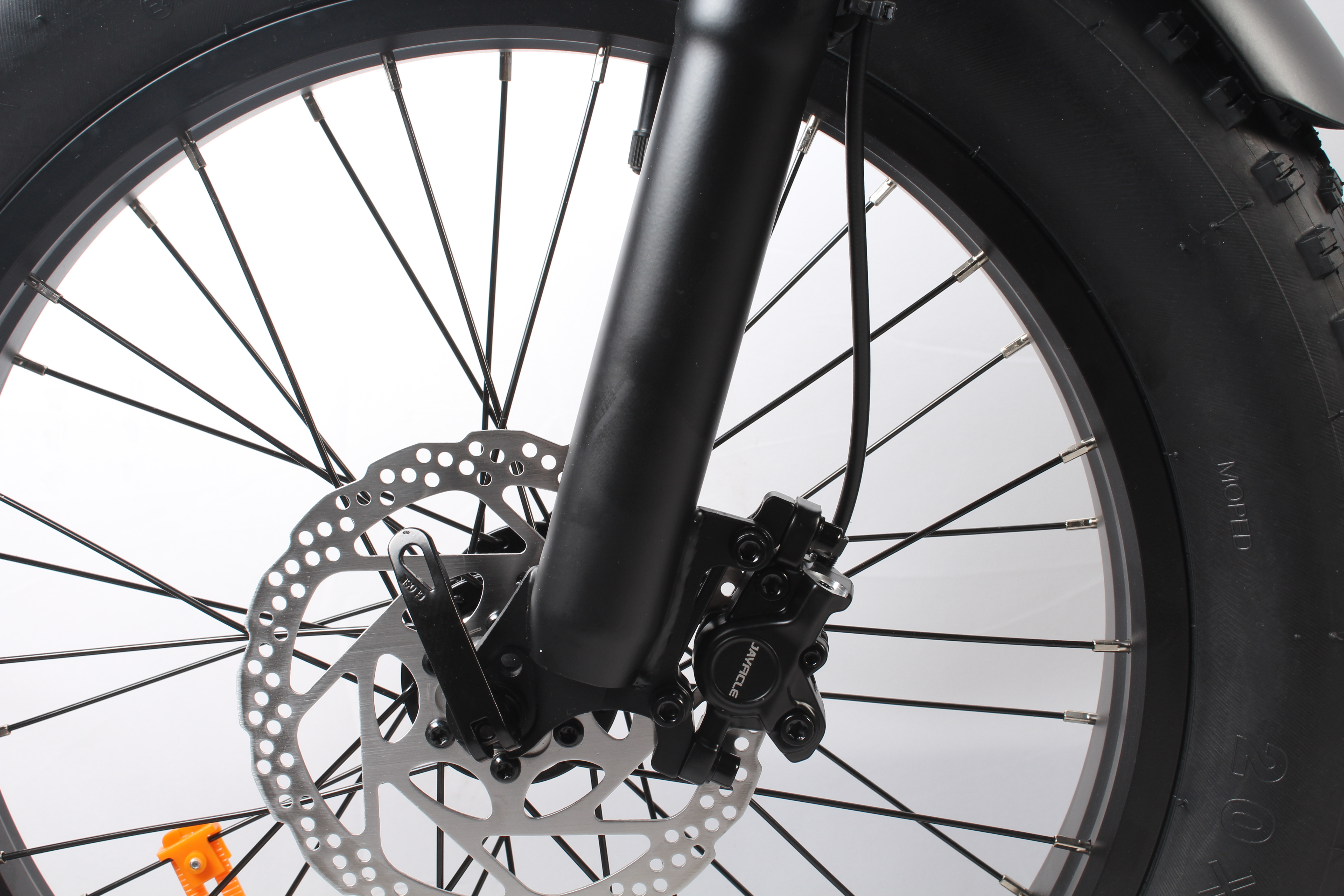 Primo piano di una ruota di bicicletta con freno a disco. Il pneumatico è nero, il cerchio è argento e il freno è nero con dettagli argento.