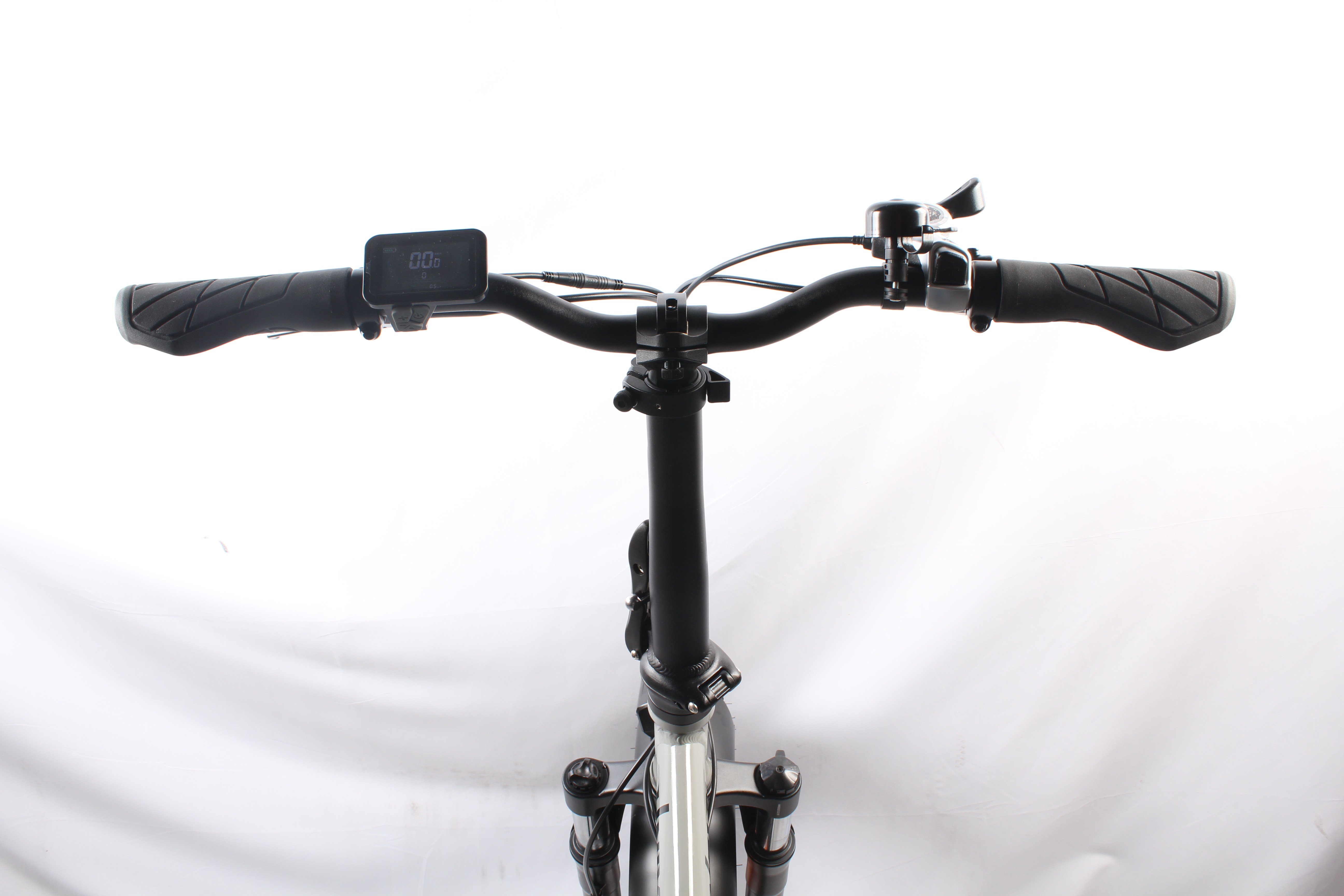 Primo piano del manubrio di una bicicletta con display e campanello. Mostra manopole nere e un telaio nero.