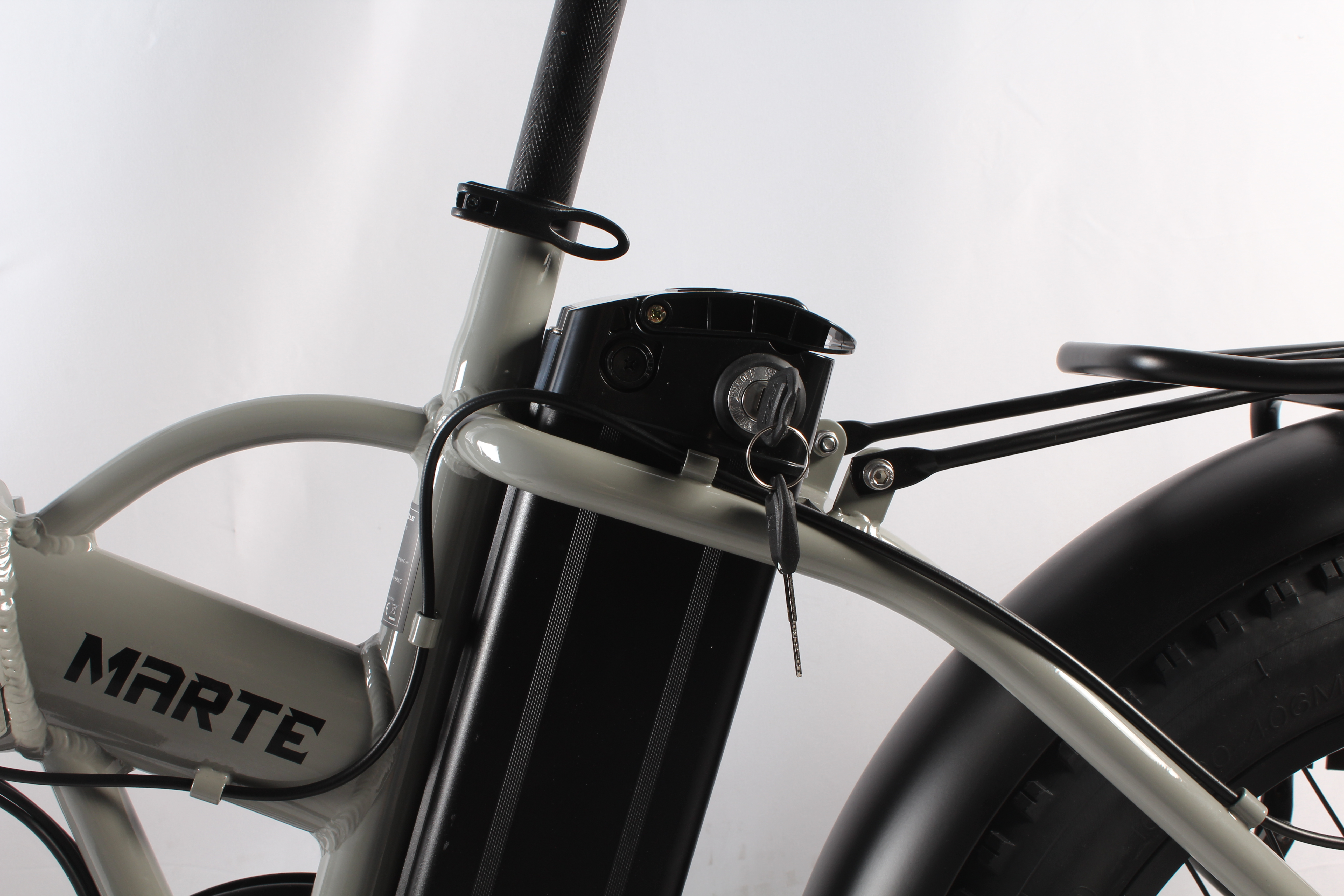 Primo piano di una bici elettrica grigia. La chiave è nell'accensione. Sul telaio c'è scritto MARTE.