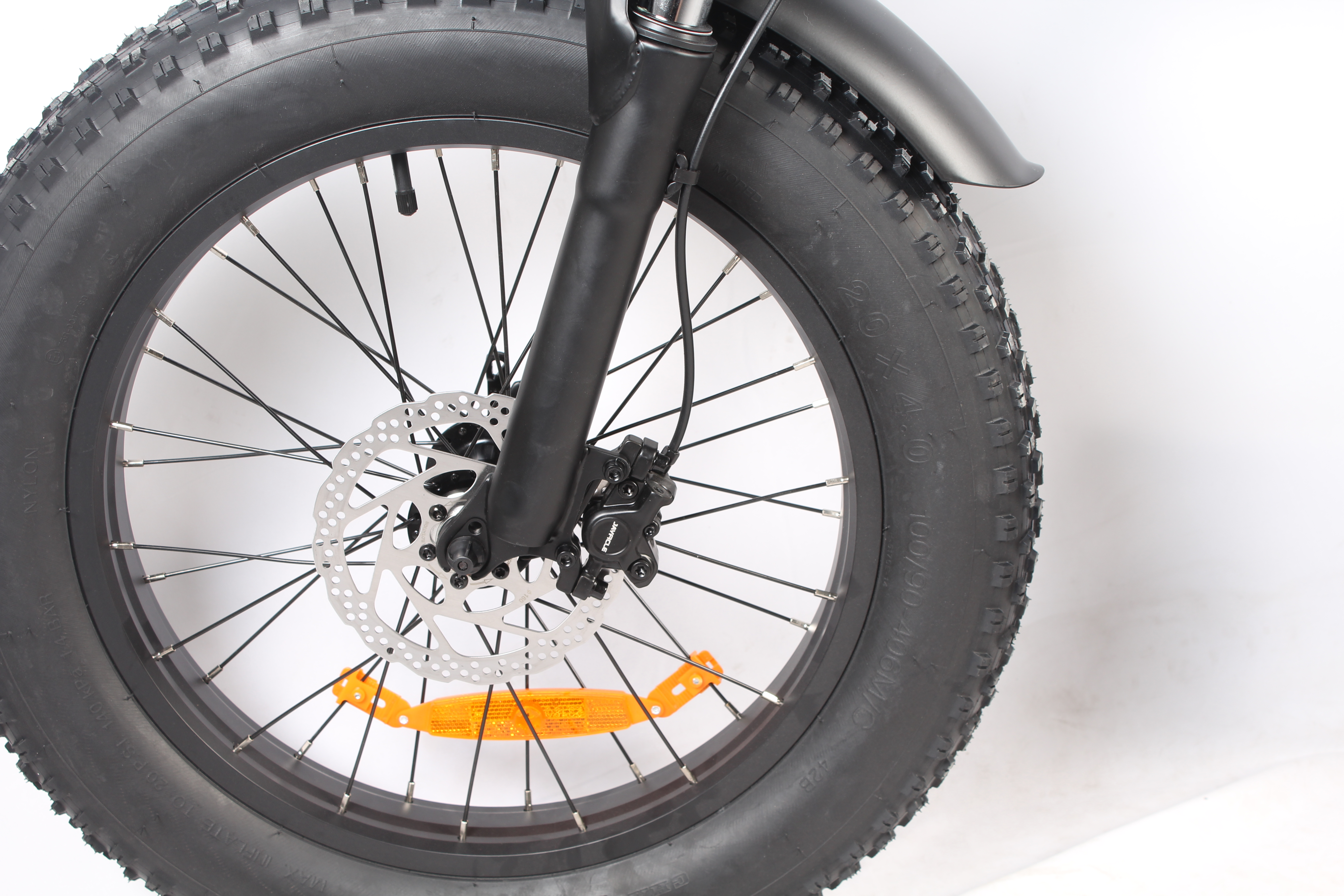 Primo piano di una ruota di bicicletta nera con pneumatico nero, raggi argentati e freno a disco argentato.