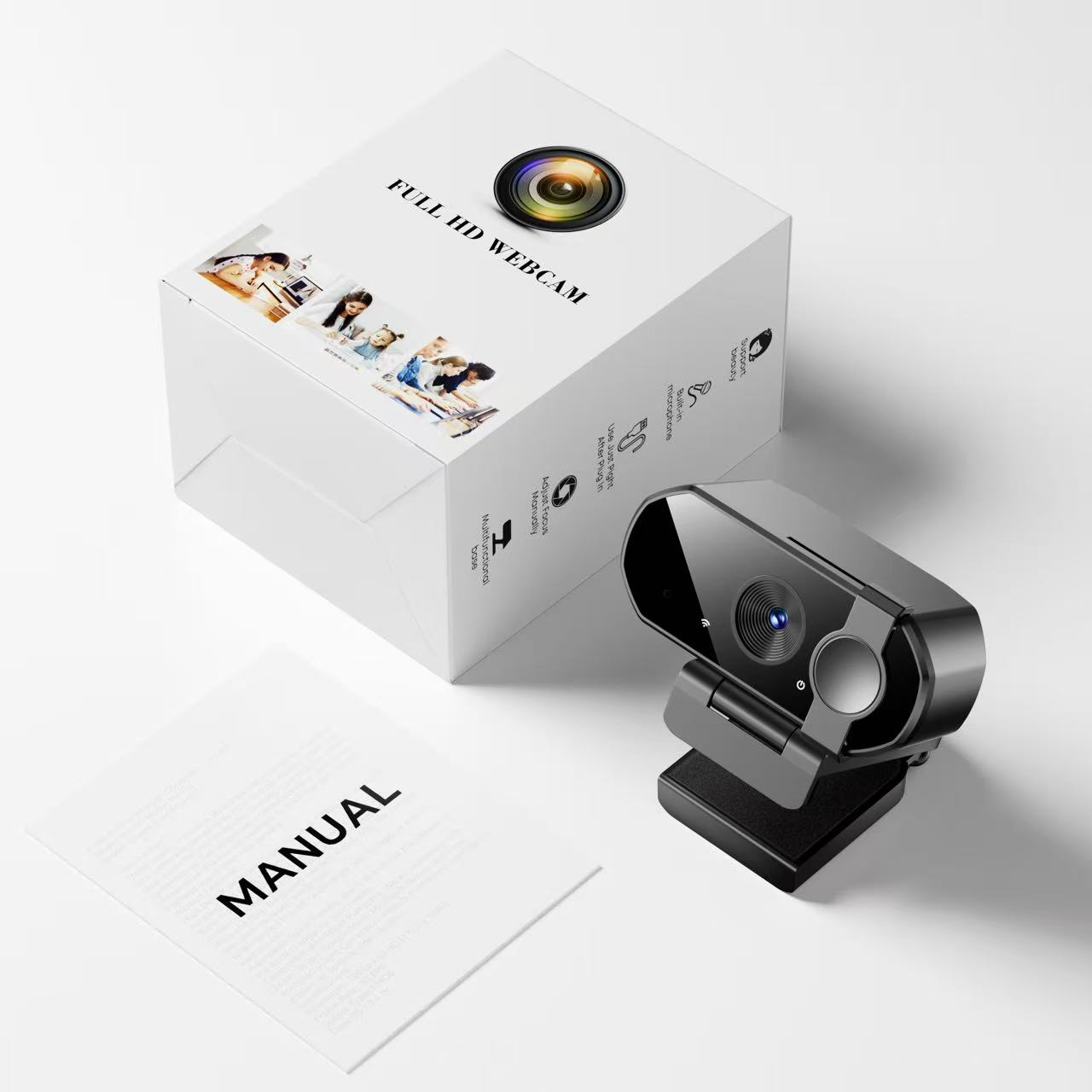 Eine Webcam, eine Box und ein Handbuch liegen auf einer weißen Oberfläche. Die Webcam ist grau und schwarz. Die Box ist weiß mit Text und Bildern.