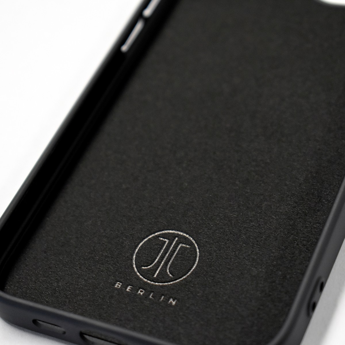 Intérieur d'étui de téléphone noir avec logo et inscription 'BERLIN'. L'étui est sur fond blanc.