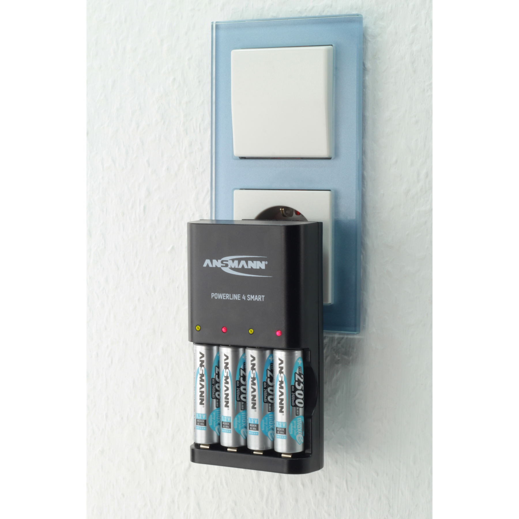 Ein schwarzes Batterieladegerät mit Batterien, eine Steckdose und ein Lichtschalter an einer weißen Wand.