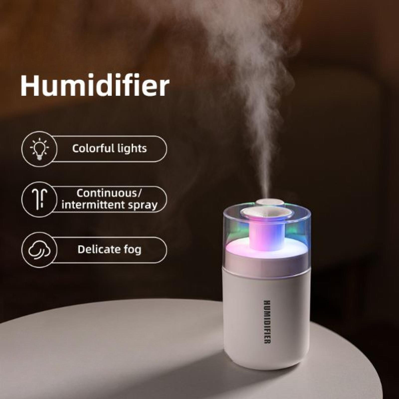 Ein weißer Luftbefeuchter mit bunten Lichtern verströmt einen feinen Nebel. Er steht auf einem weißen Tisch, dunkler Hintergrund.