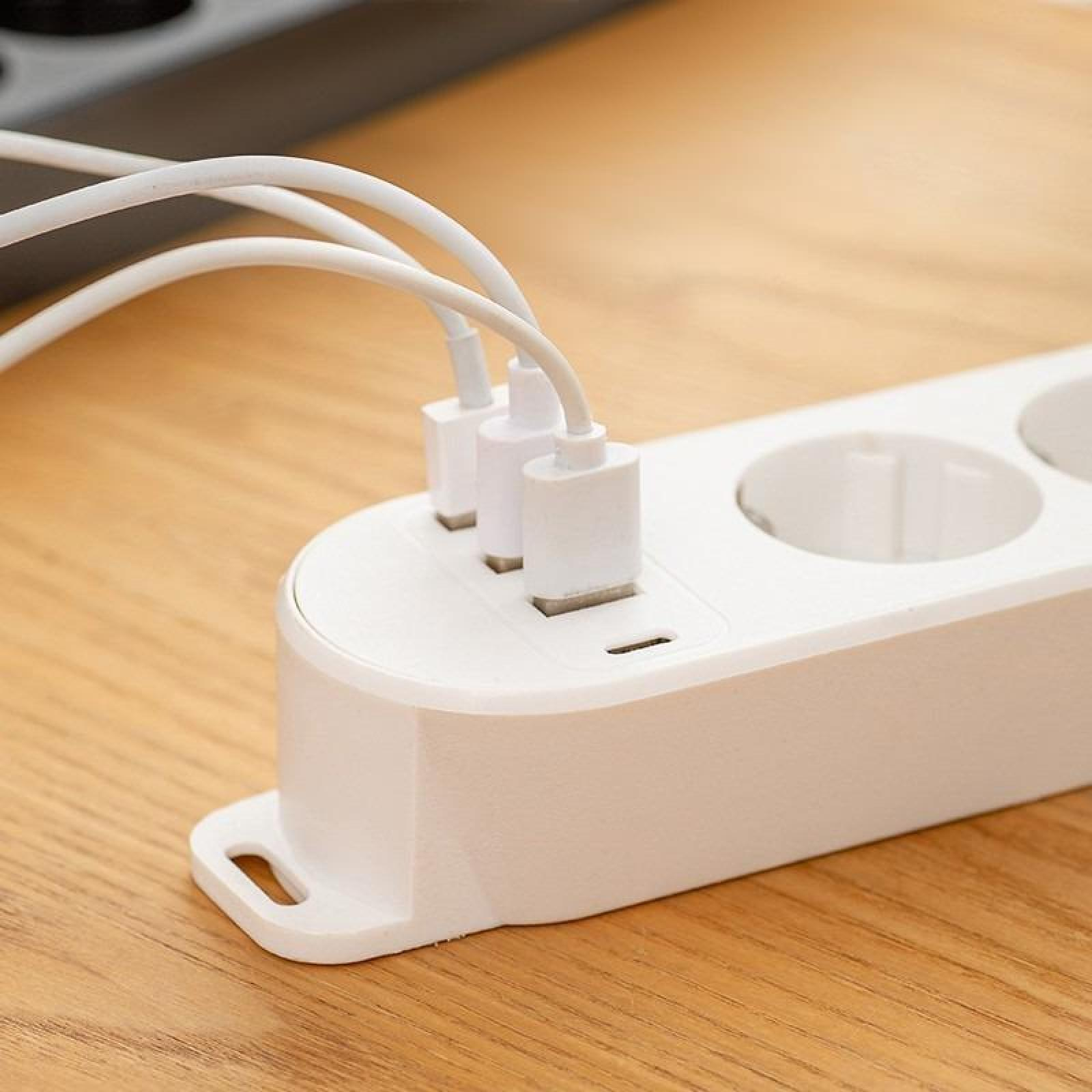 Eine weiße Steckdosenleiste mit mehreren eingesteckten USB-Kabeln. Sie liegt auf einer Holzoberfläche.