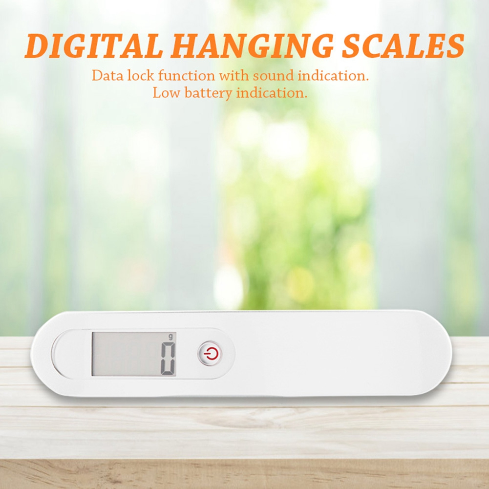 Eine weiße digitale Hängewaage zeigt '0' auf einem digitalen Bildschirm an. Sie hat einen Ein-/Ausschalter und steht auf einem Holztisch.