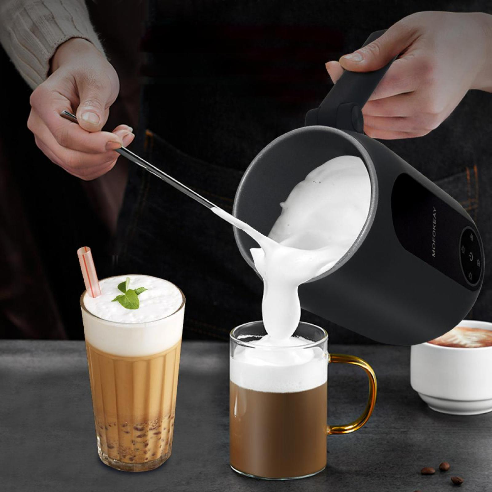 Eine Person gießt Milchschaum in einen Kaffebecher. Daneben befinden sich Kaffeegetränke, eines mit Strohhalm, das andere mit Minzblatt.