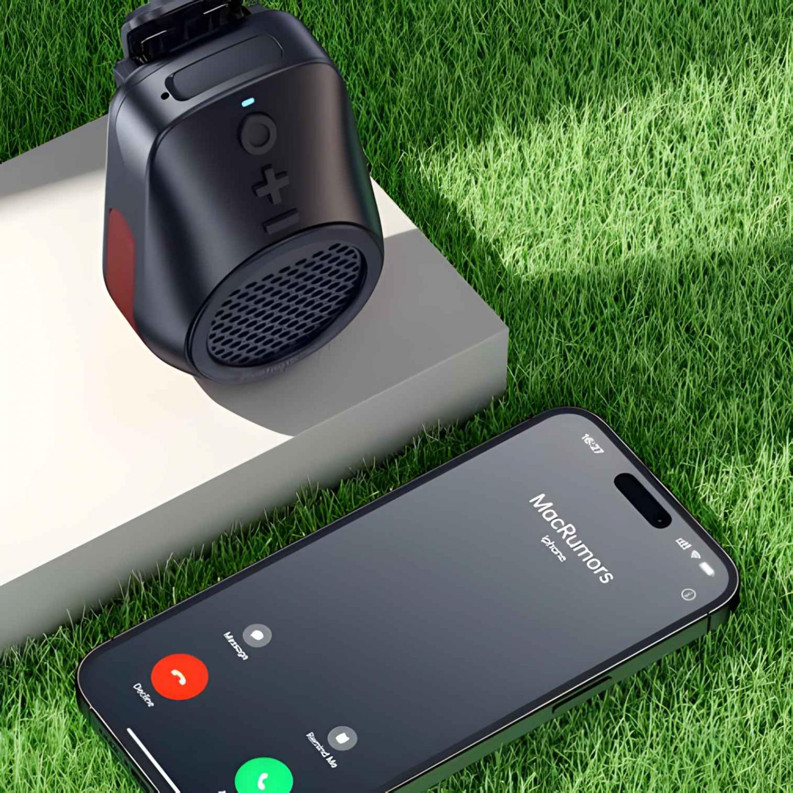 Schwarzer Lautsprecher und iPhone auf Gras. iPhone zeigt einen Anrufbildschirm. Der Lautsprecher steht auf einer weißen Plattform.