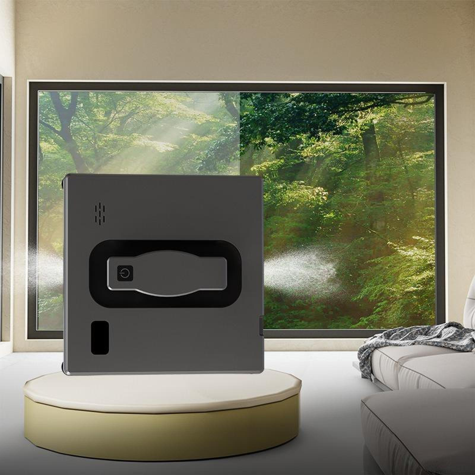 Ein grauer Fensterputzroboter auf einem Sockel reinigt ein Fenster mit Blick auf einen Wald.