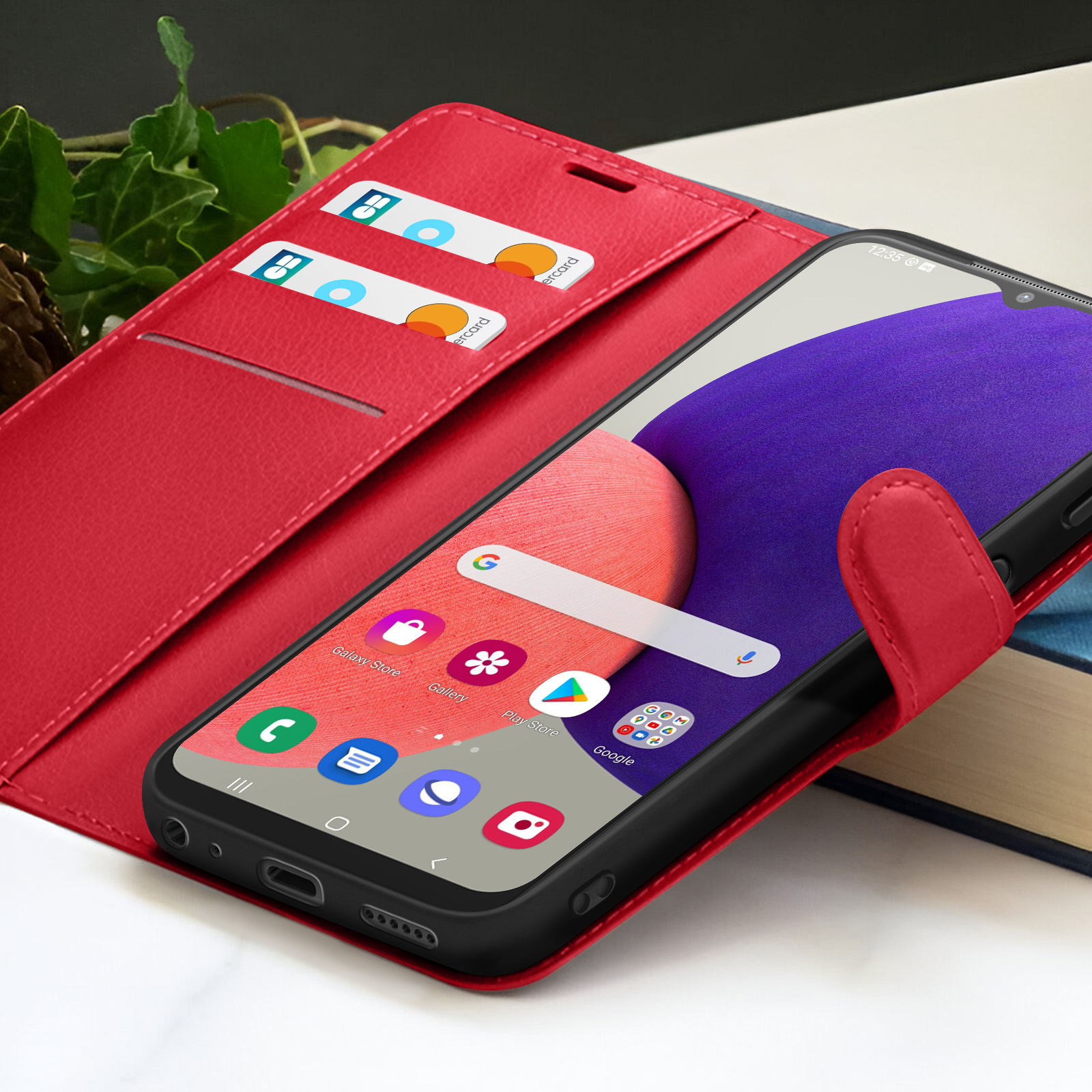 Een rode telefoonhoes met een smartphone erin en twee creditcards. Het scherm toont apps.