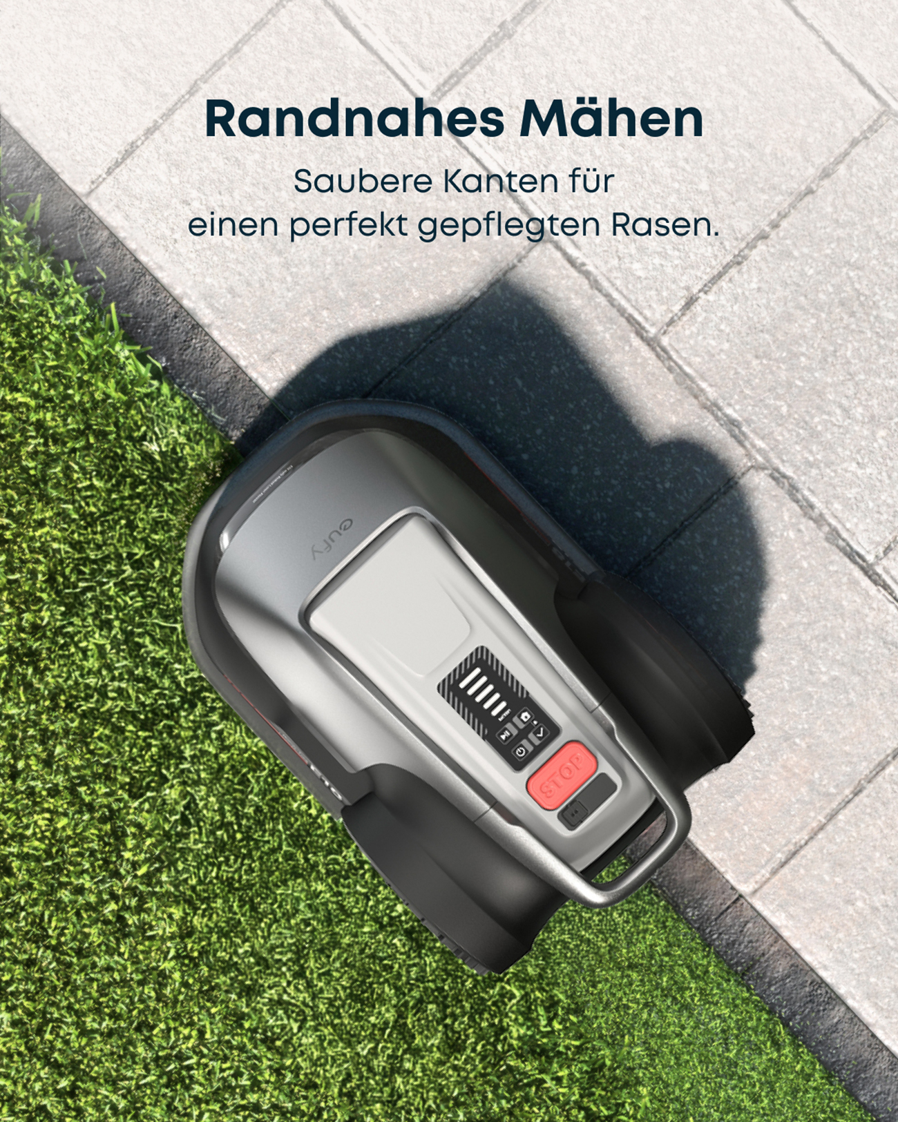 Ein Roboter-Rasenmäher auf grünem Gras neben einem gepflasterten Gehweg. Der Mäher ist grau mit rotem Stopp-Knopf. Text ist darüber.