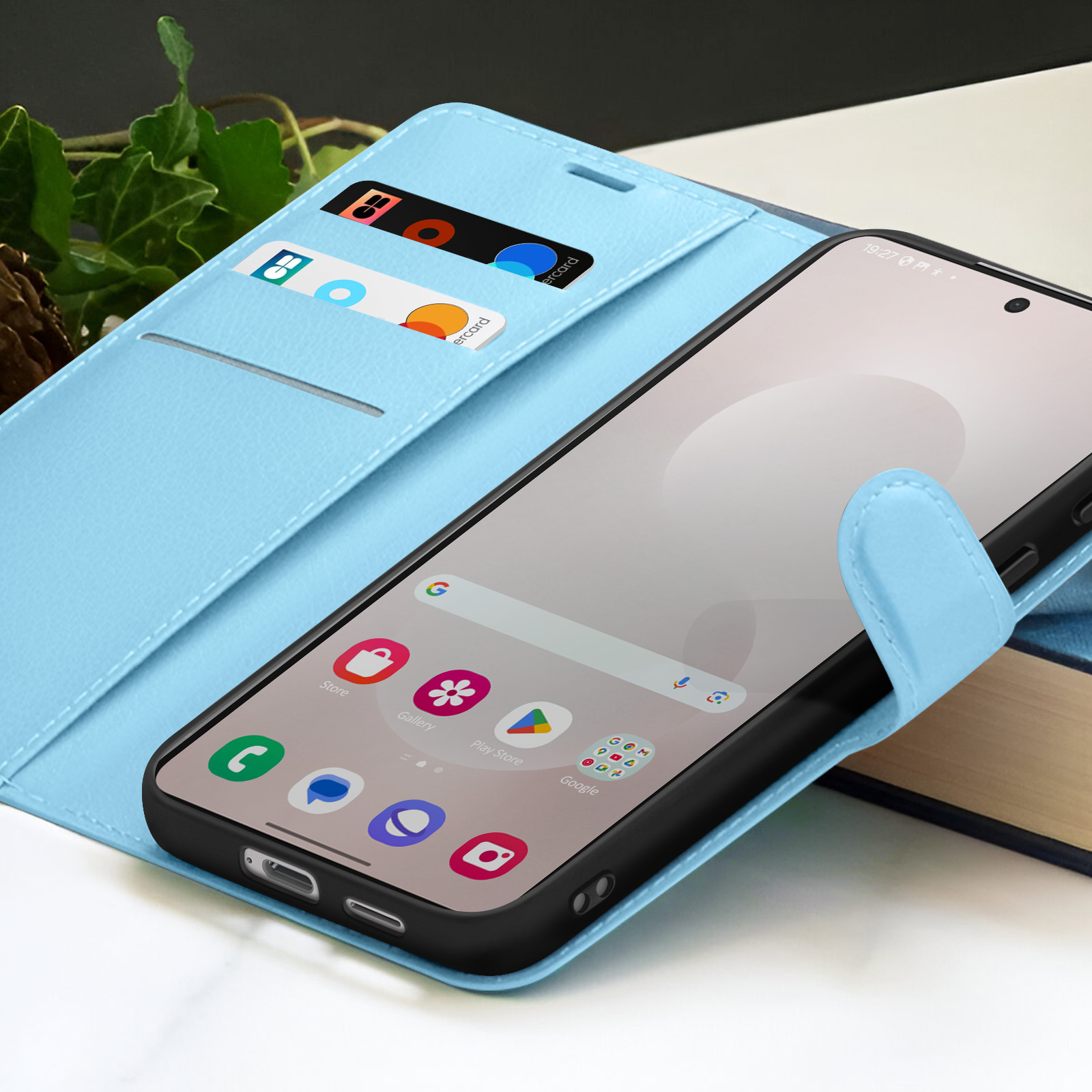 Un smartphone dans un étui bleu clair. Des cartes sont visibles dans l'étui. L'écran affiche des icônes d'applications.