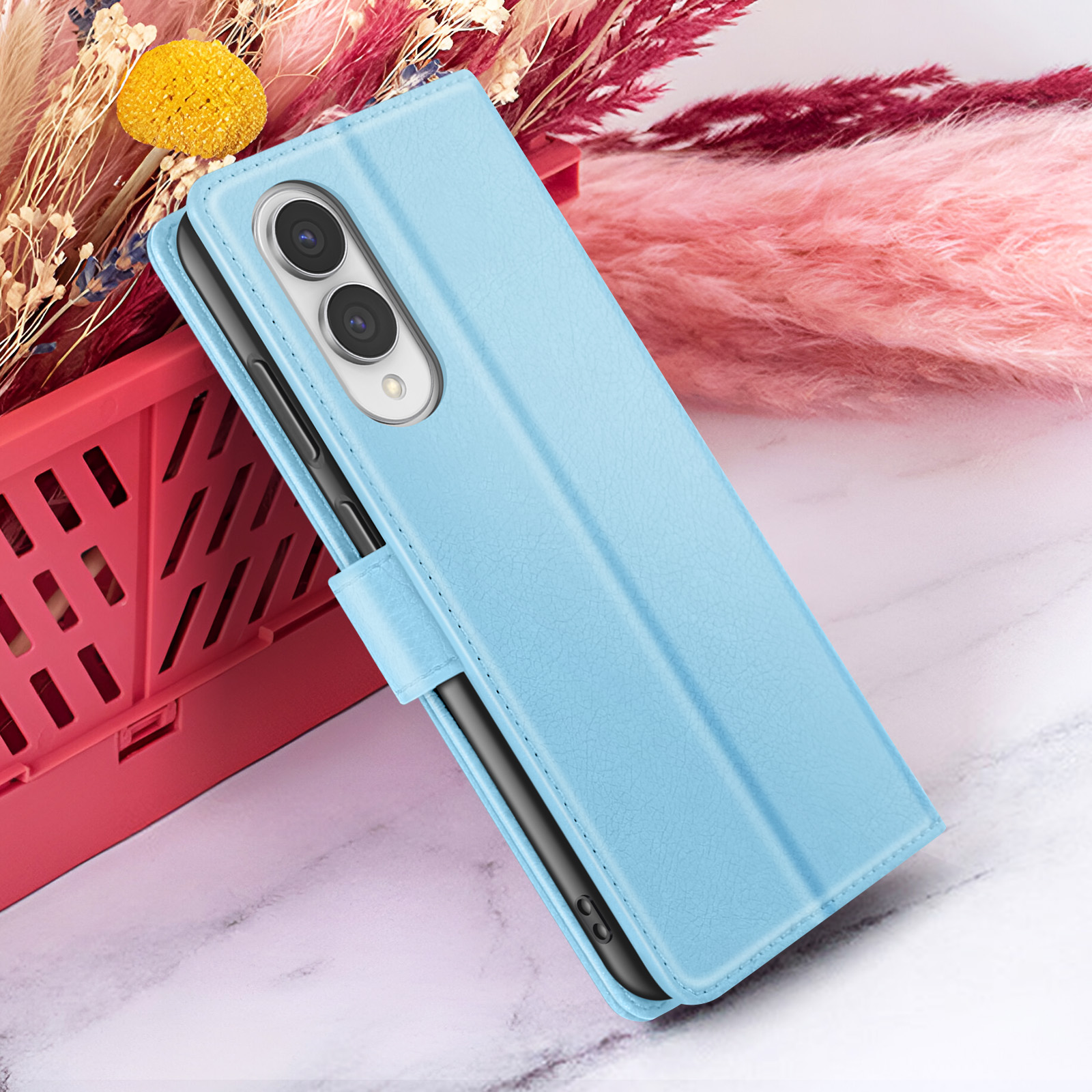 Un étui de téléphone bleu clair avec un téléphone à l'intérieur, devant un fond floral rose et rouge.