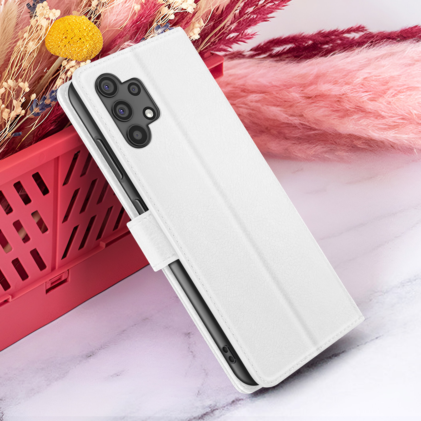 Witte telefoonhoes met meerdere camera's, open, rustend op een wit oppervlak met bloemen en een rode mand.