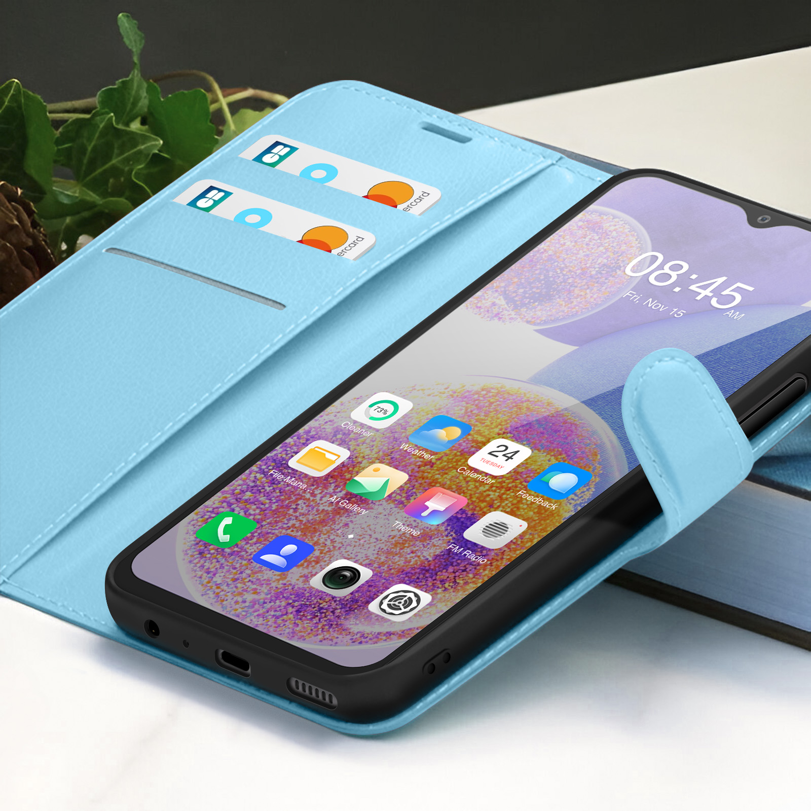 Ein Smartphone in hellblauer Hülle, das die Uhrzeit 08:45 anzeigt. Karten befinden sich im Etui. Apps sind auf dem Bildschirm.