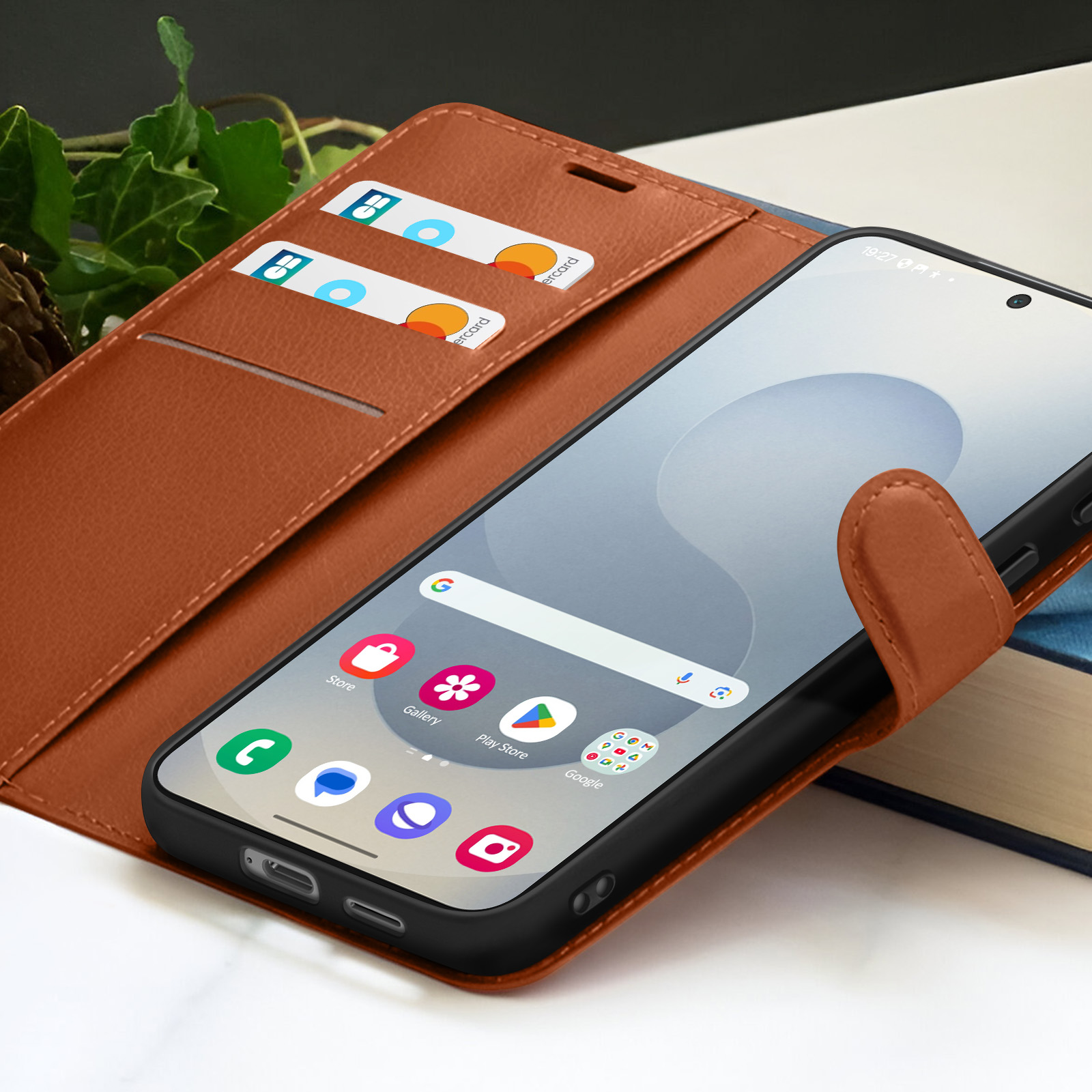 Een smartphone in een bruine lederen hoes, met creditcards en een boek op de achtergrond. Pictogrammen zijn zichtbaar op het scherm.