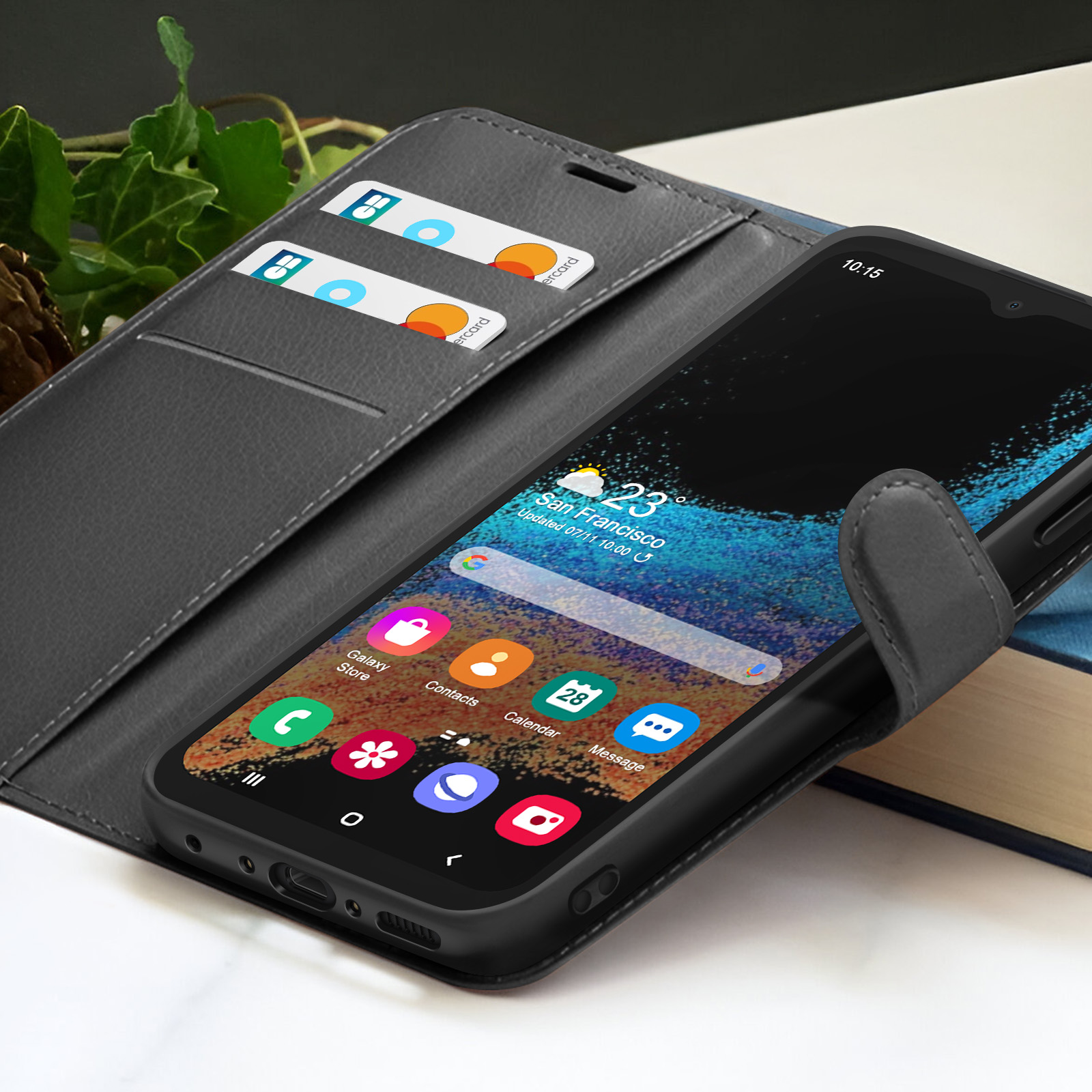Een zwarte smartphone in een grijze leren hoes toont het startscherm met app-iconen en kaarten. Twee creditcards zijn zichtbaar.