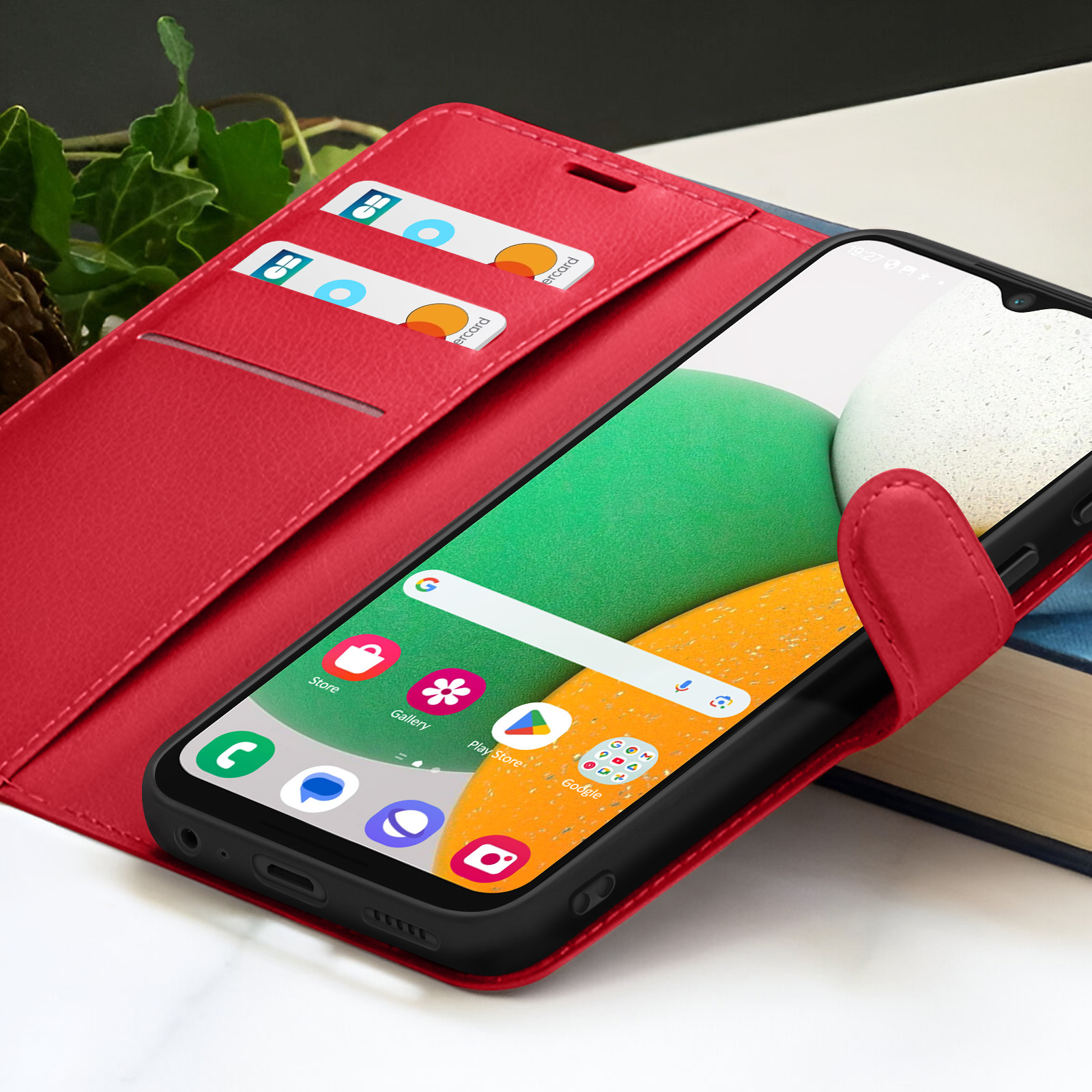 Custodia rossa per telefono con telefono che mostra le app. Due carte di credito sono nella custodia. Lo sfondo è sfocato.