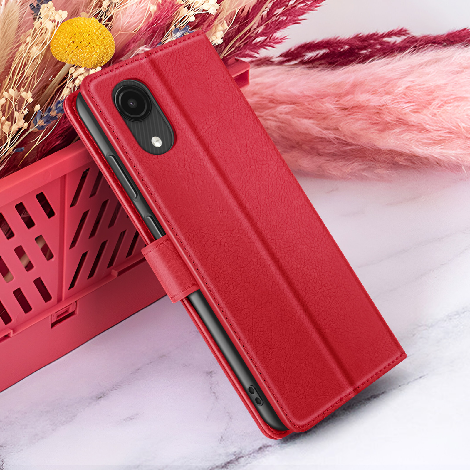 Una custodia rossa per telefono con un telefono all'interno, su uno sfondo di fiori e marmo.