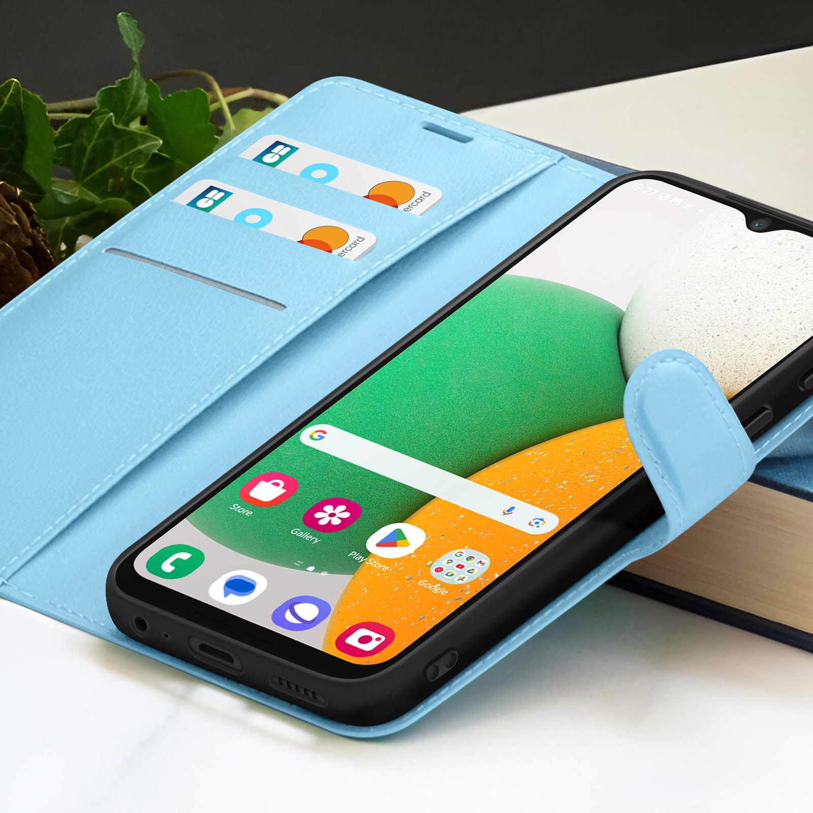 Smartphone in una custodia azzurra con carte. Lo schermo mostra app e una barra di ricerca di Google. Sfondo sfocato.