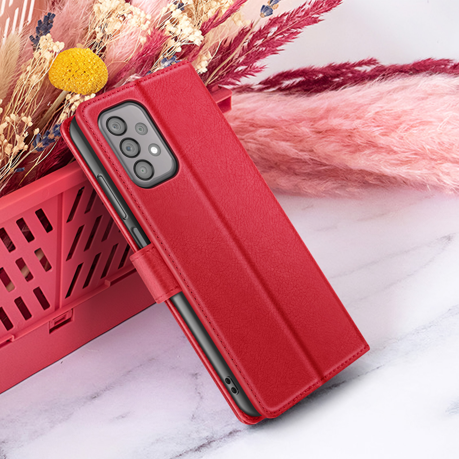Una custodia rossa per telefono con telefono all'interno, su sfondo di fiori e marmo.