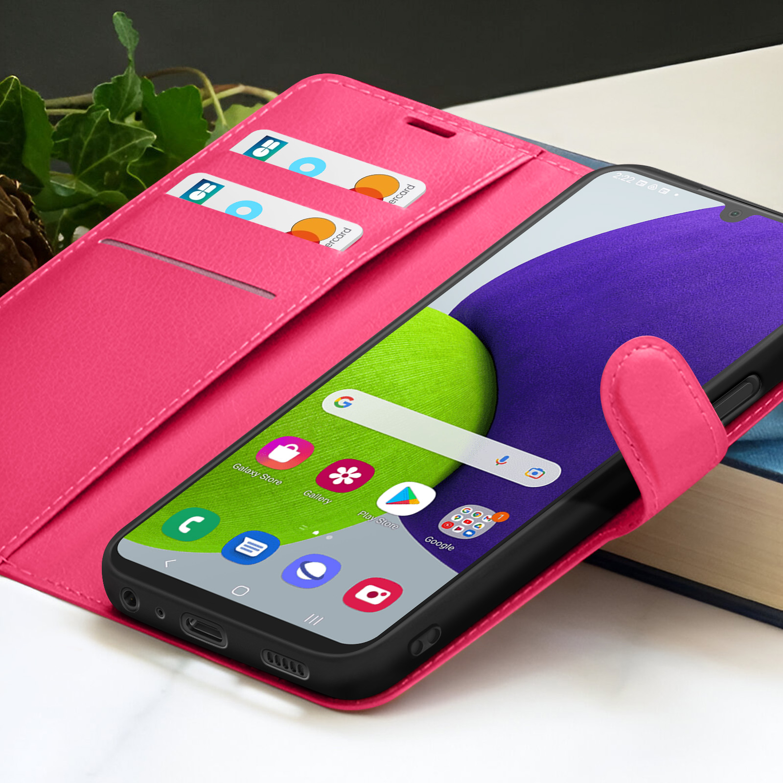 Een roze telefoonhoesje met een telefoon waarop app-iconen worden weergegeven. Twee creditcards zitten in de hoes.