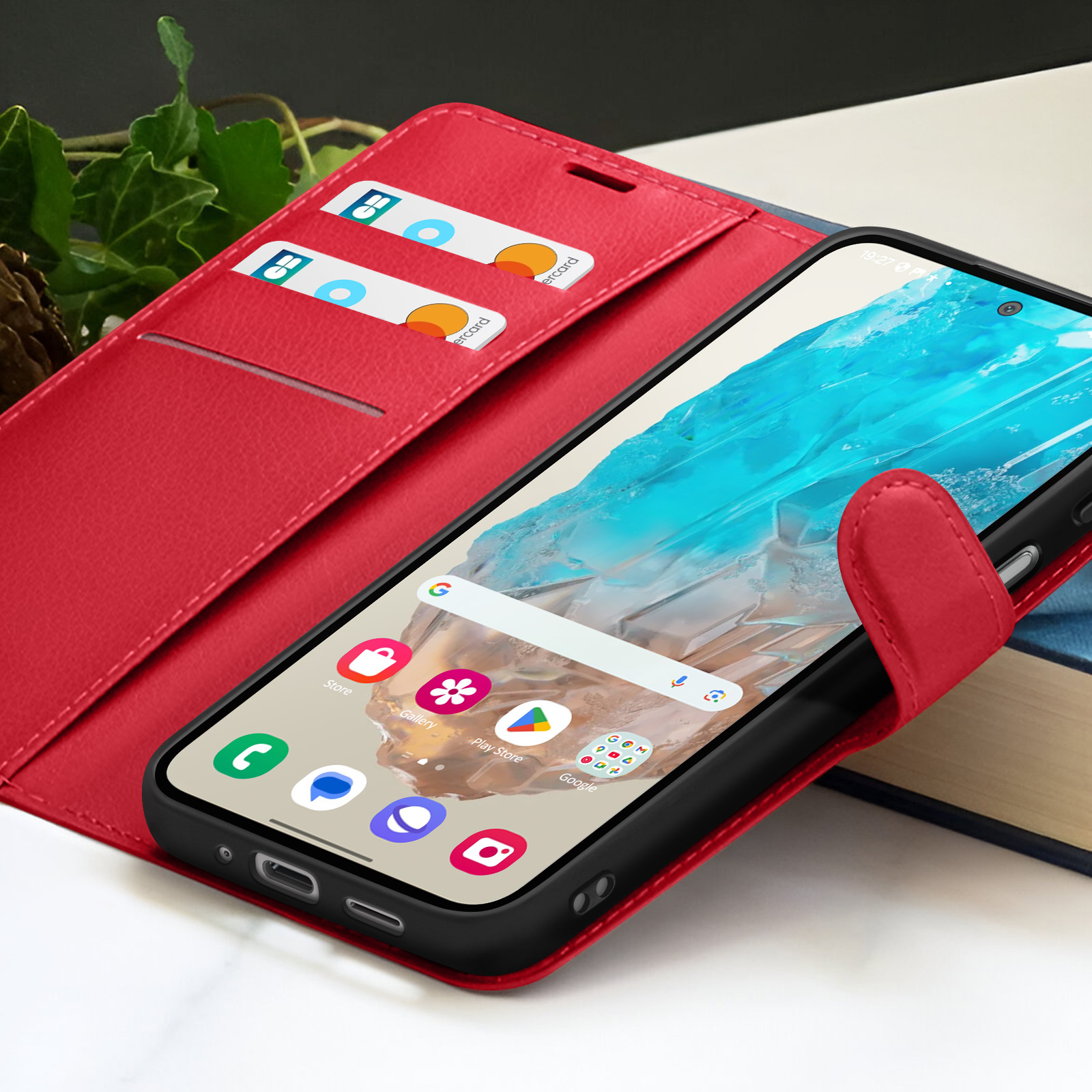 Rode telefoonhoes met smartphone erin. Twee kaarten zichtbaar. Scherm toont apps.