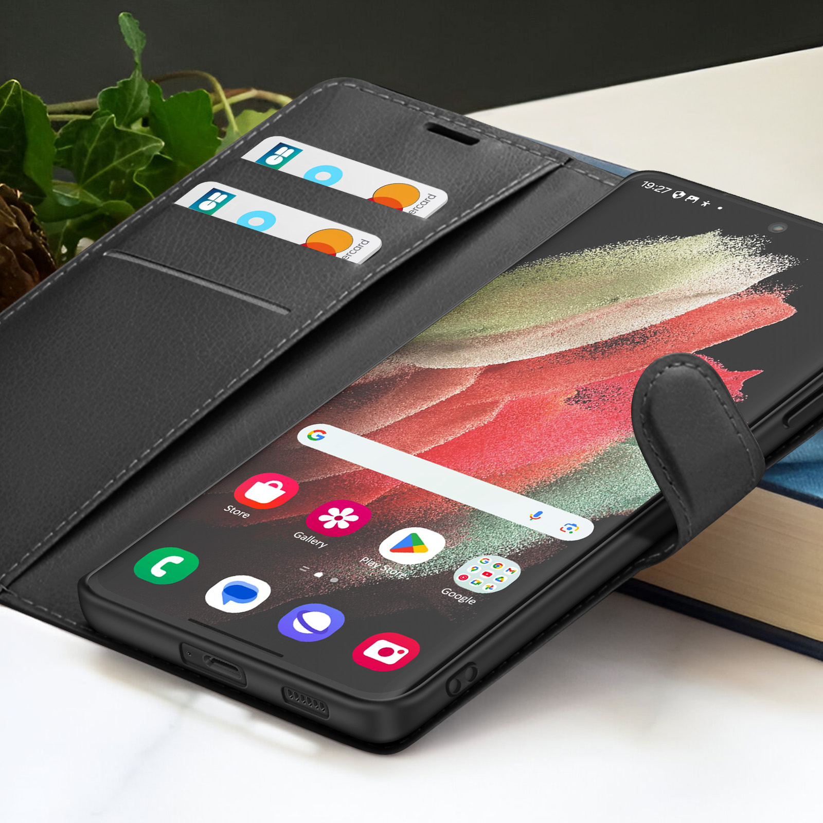 Een zwarte smartphone in een zwarte leren hoes, met creditcards en iconen zichtbaar. Het scherm toont een Google zoekbalk.