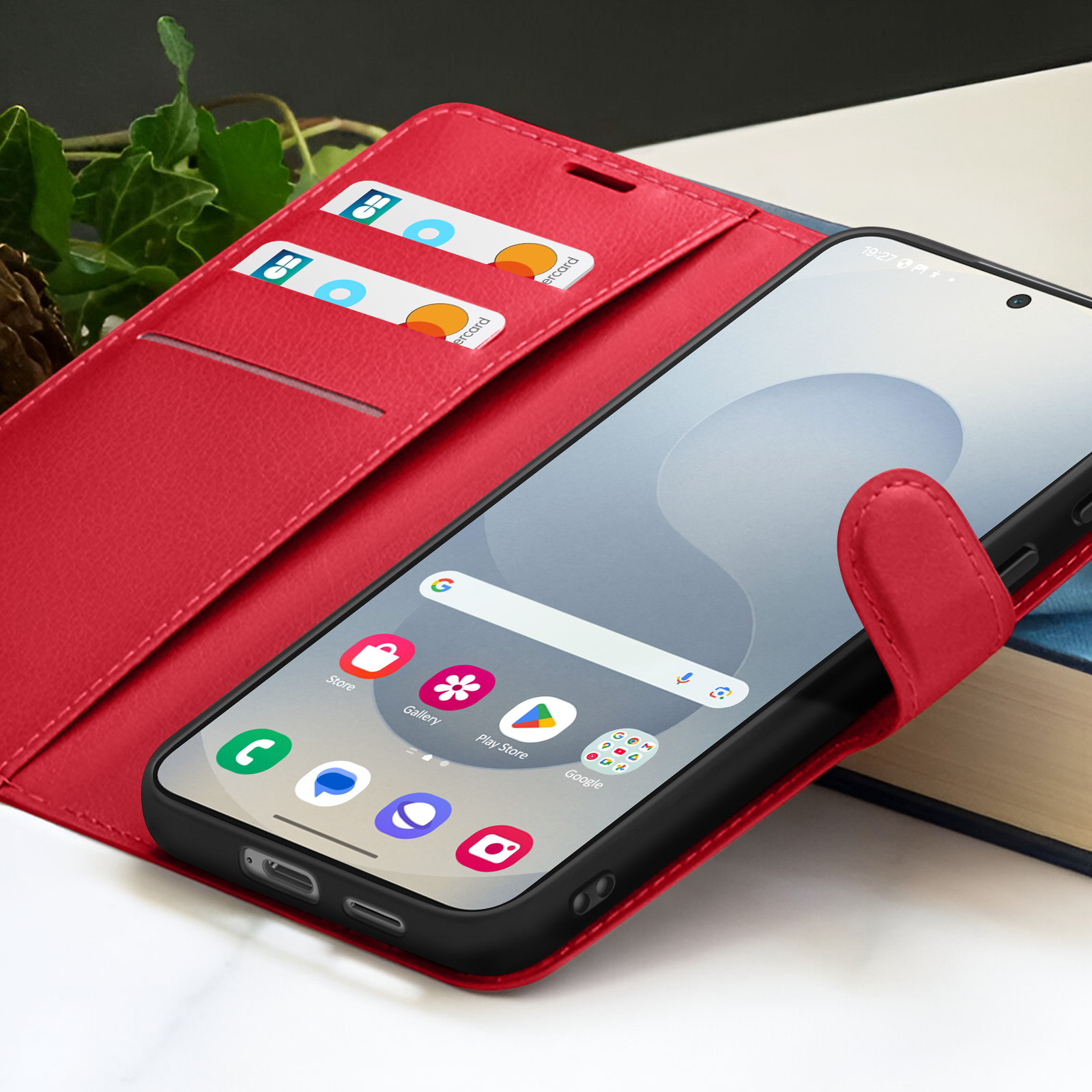 Een rode telefoonhoes met een telefoon erin. Er zitten creditcards in de hoes. De telefoon geeft app-iconen weer.
